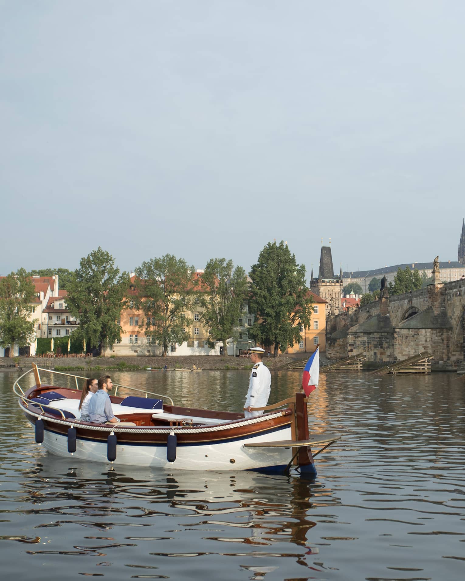 Couple enjoy river boat trip in Prague near small bridge