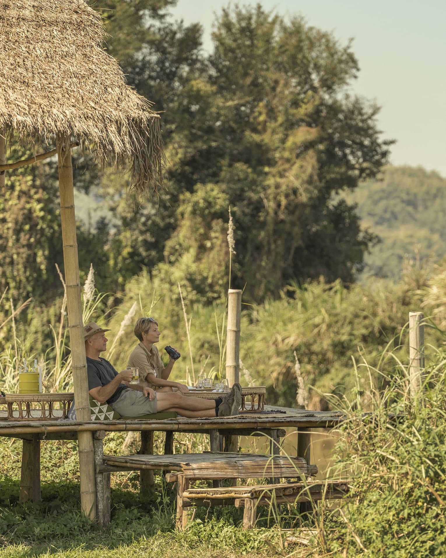 Couple enjoys a camp picnic with views of Thailand's rolling green hills