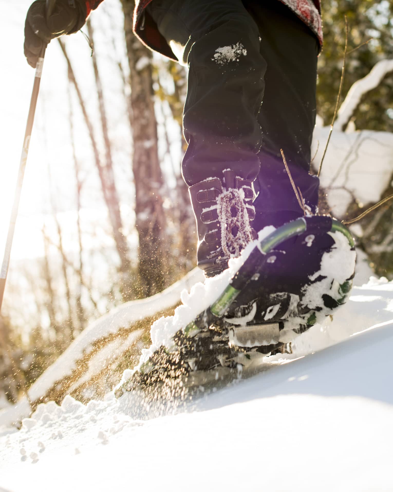 A person walking on snow using snow shoes and poles to help them walk.