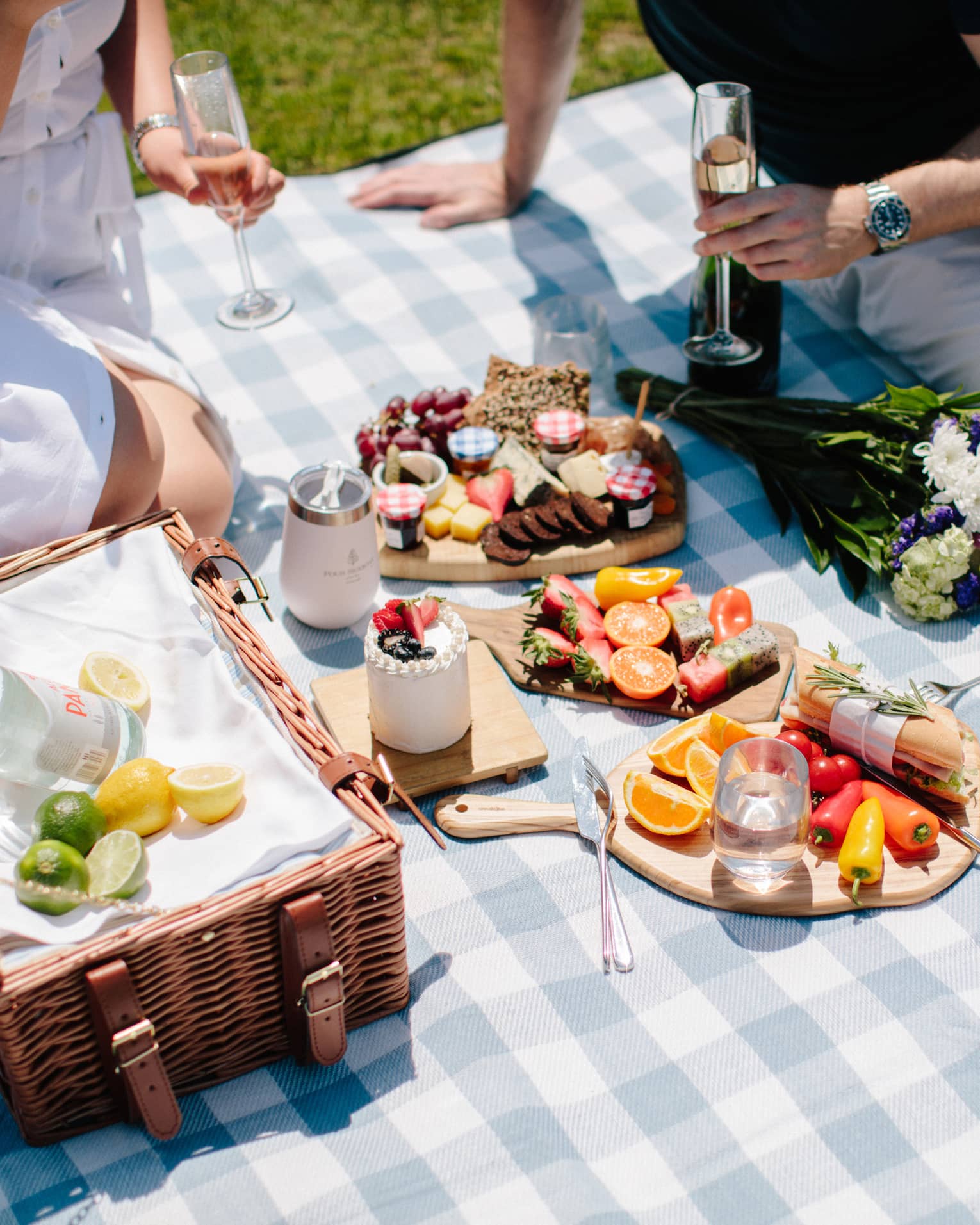 Two people enjoying a large picnic in a park during a sunny day.