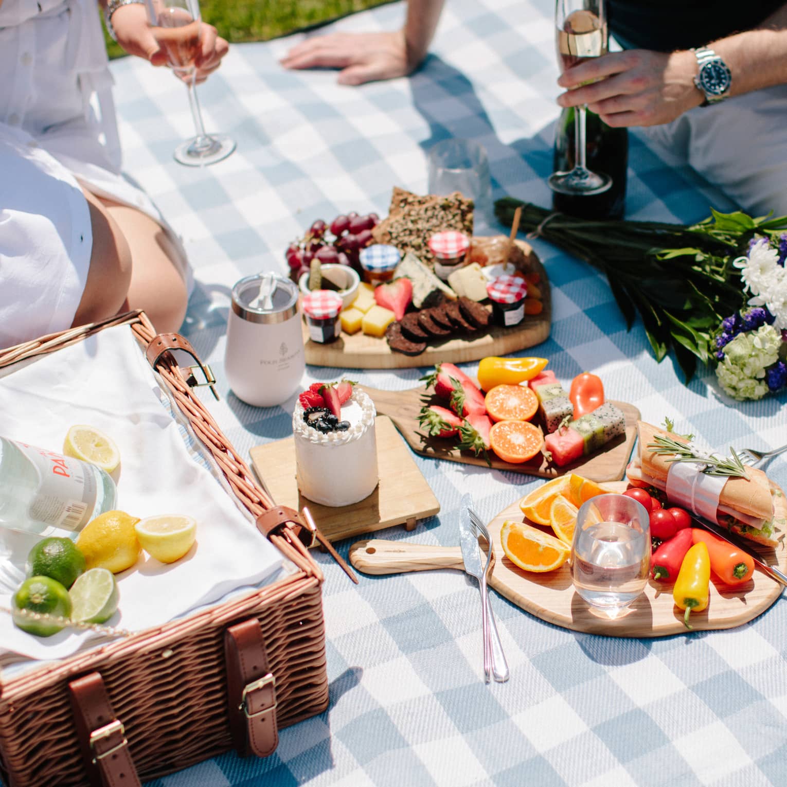 Two people enjoying a large picnic in a park during a sunny day.