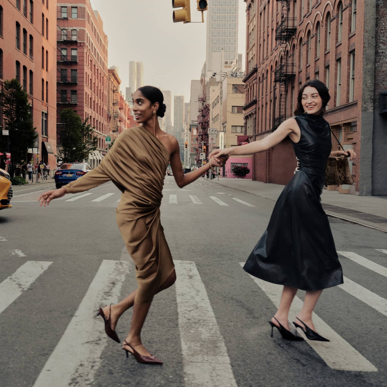 Two women holding hands cross a street in New York City.