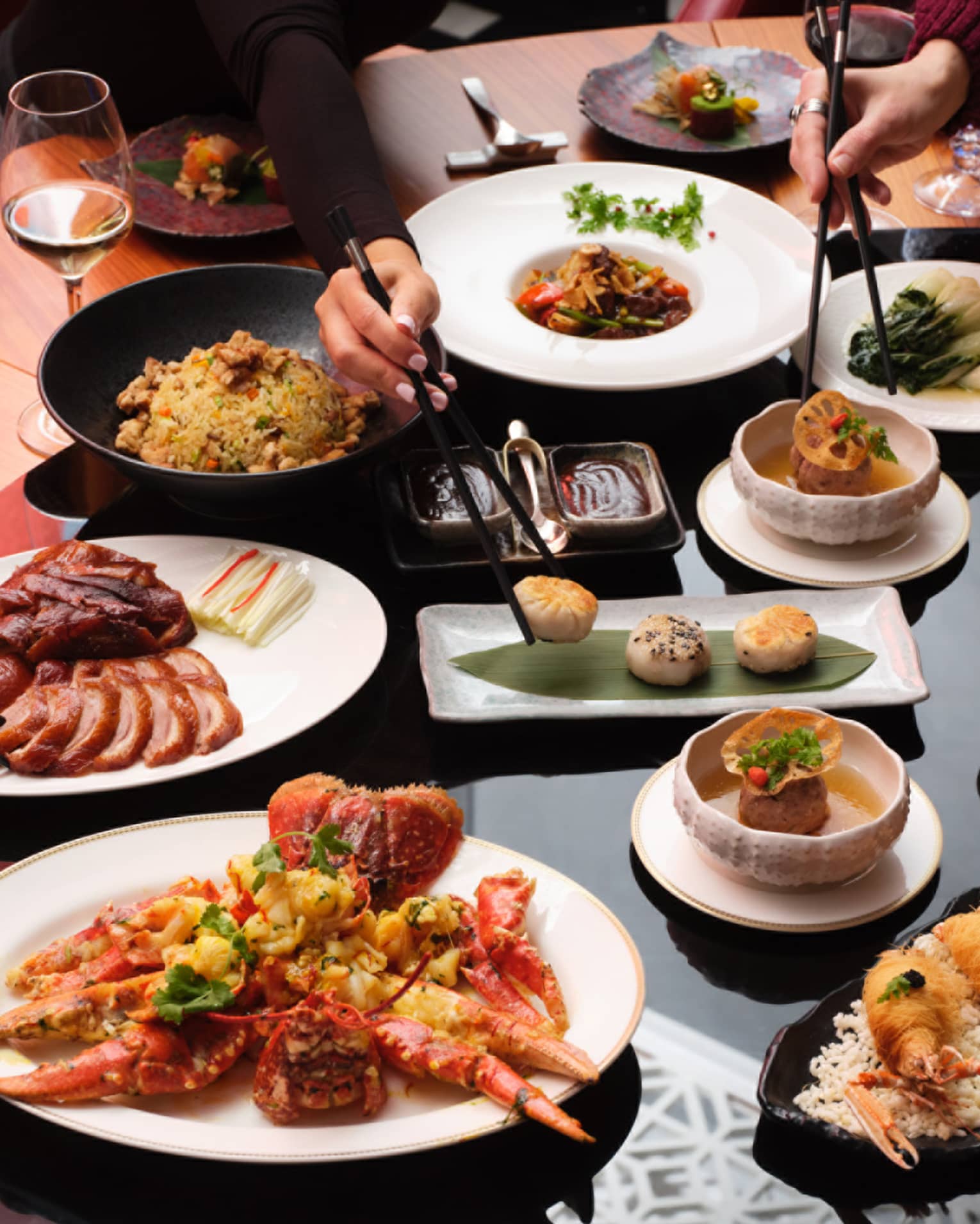 Round dining table with various dishes that people share, including meat and fried shellfish