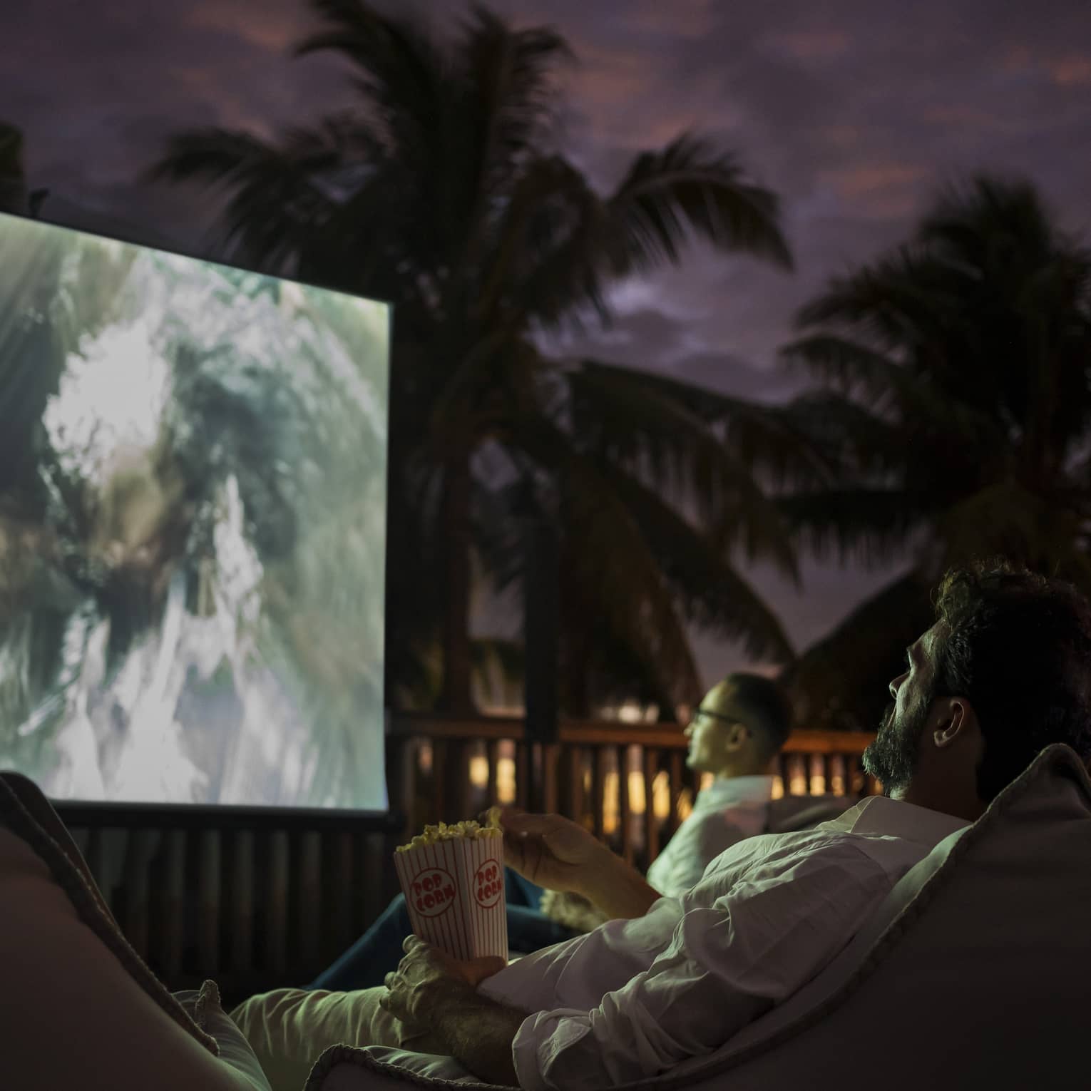 Group of people sit on bean bags with popcorn watching movie under the stars