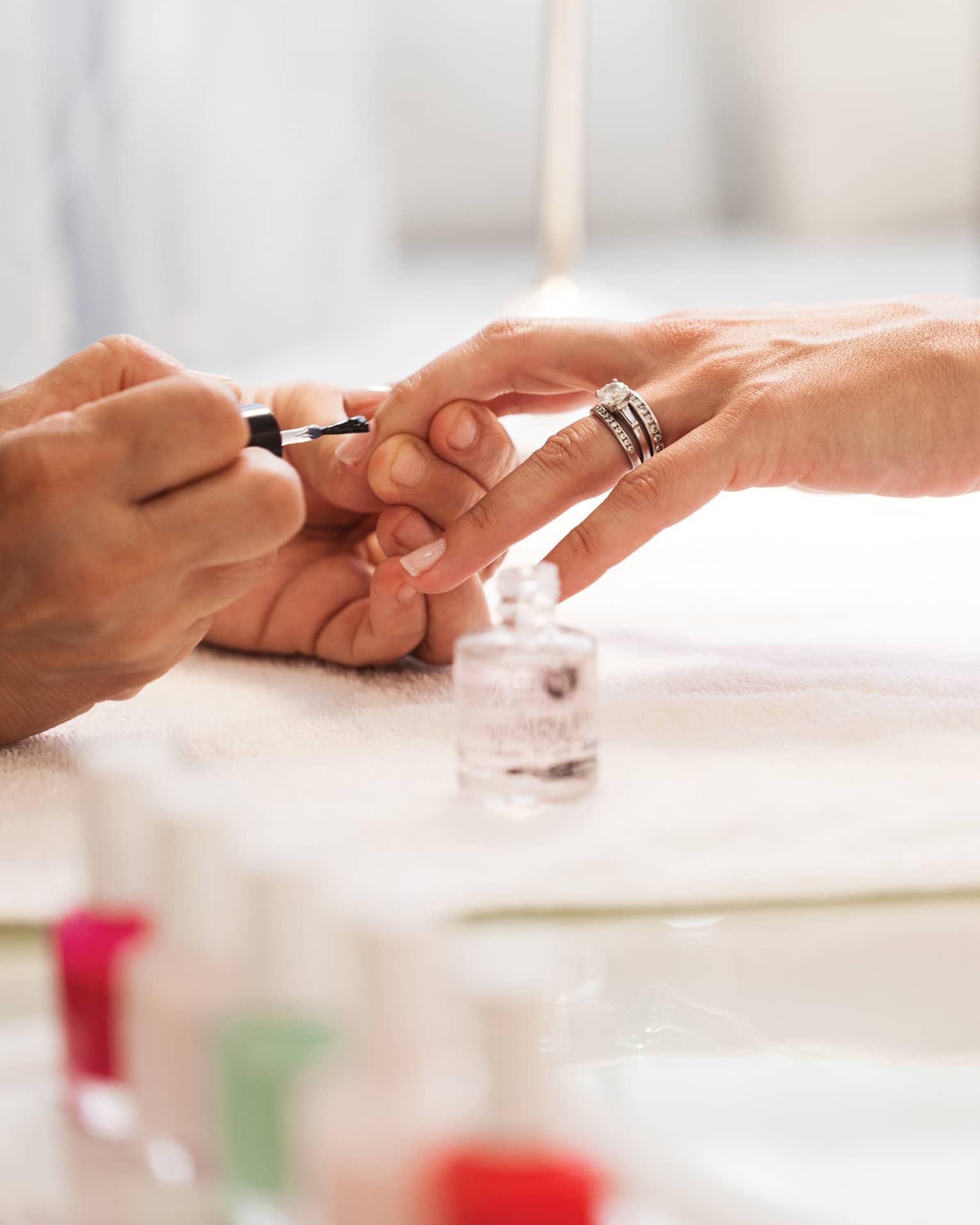 Close-up of woman in white robe getting clear polish manicure at spa table