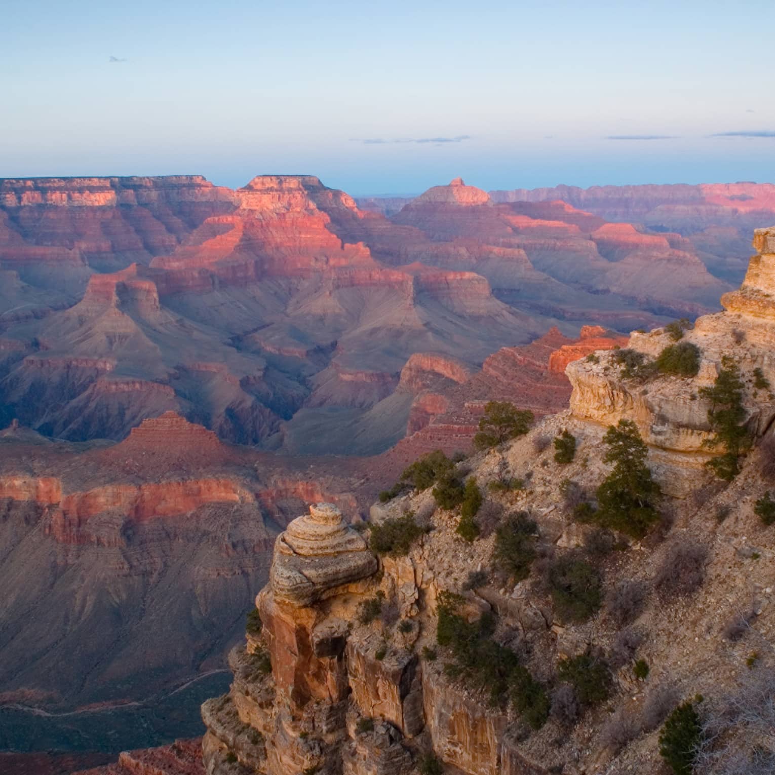 Sweeping view of Grand Canyon cliffs, canyon ridges, pink light from sunset