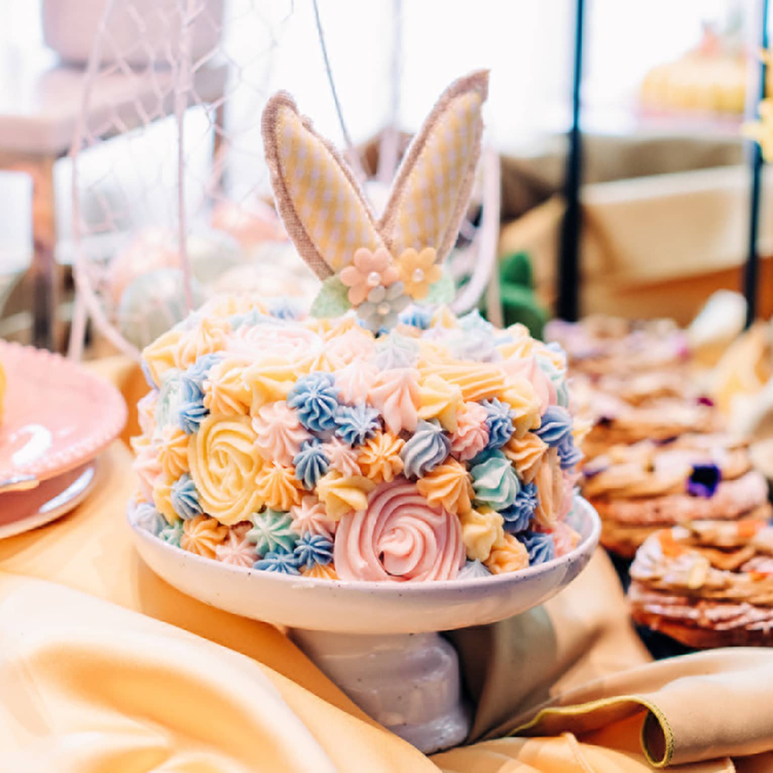 A cake with yellow, blue and pink icing and bouquets of flowers