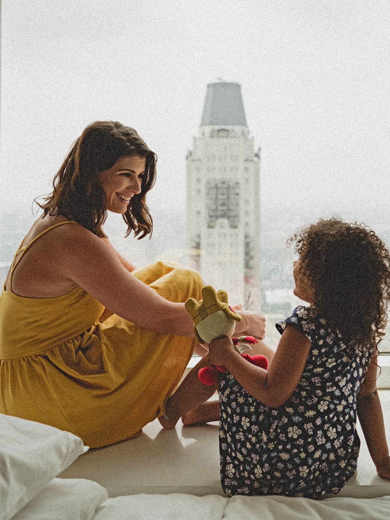 A woman and a small child sitting by a large window.