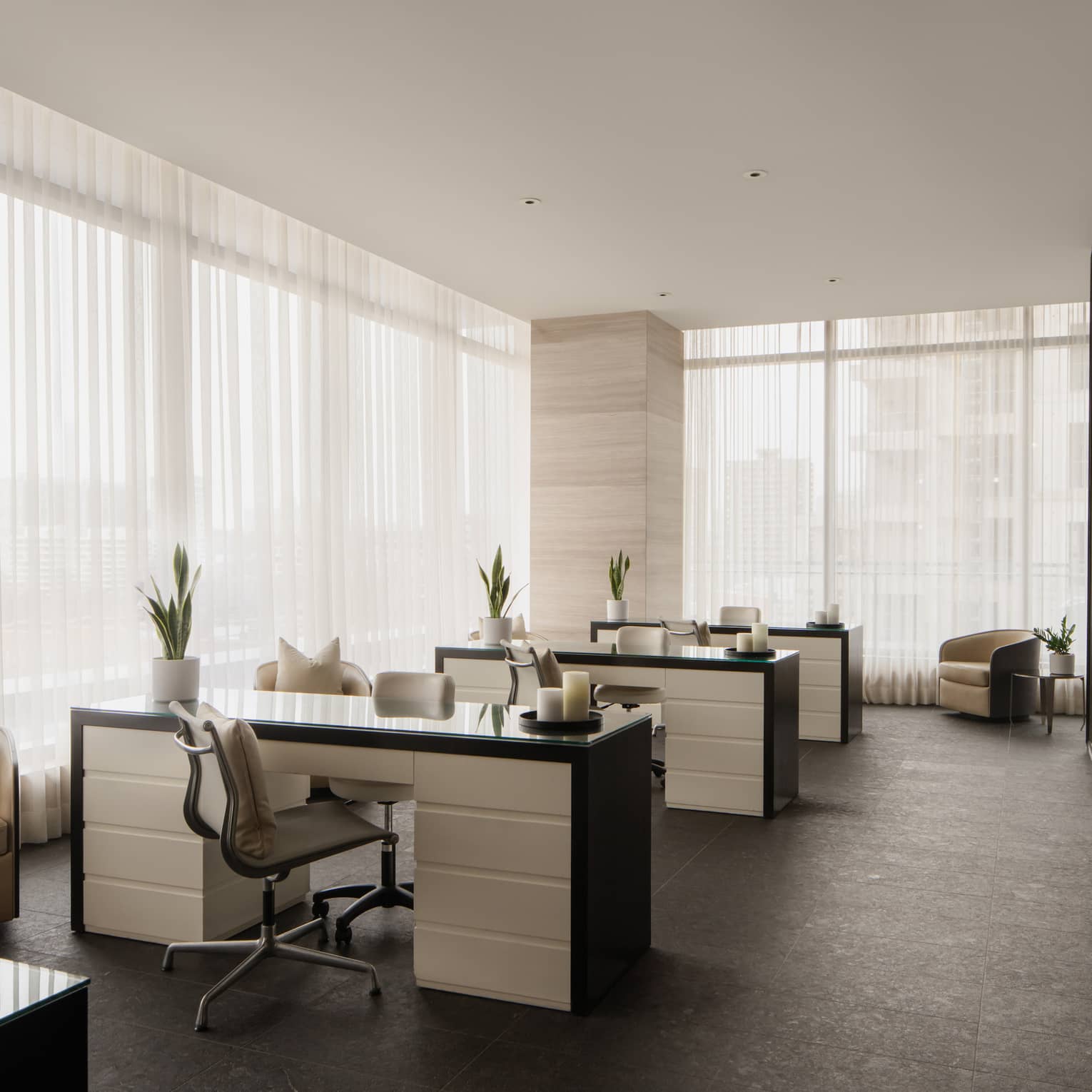 Nail salon with three black and white stations, floor-to-ceiling windows with sheer white curtains