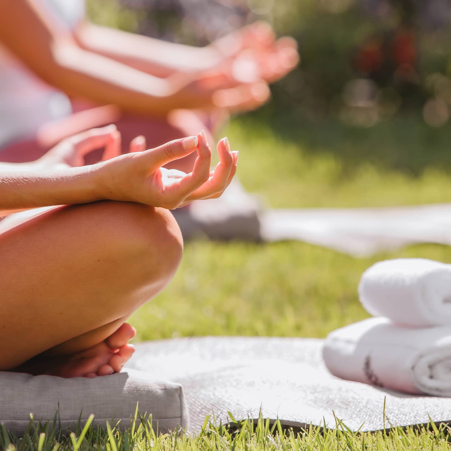 A group doing yoga outside with mats and towels.