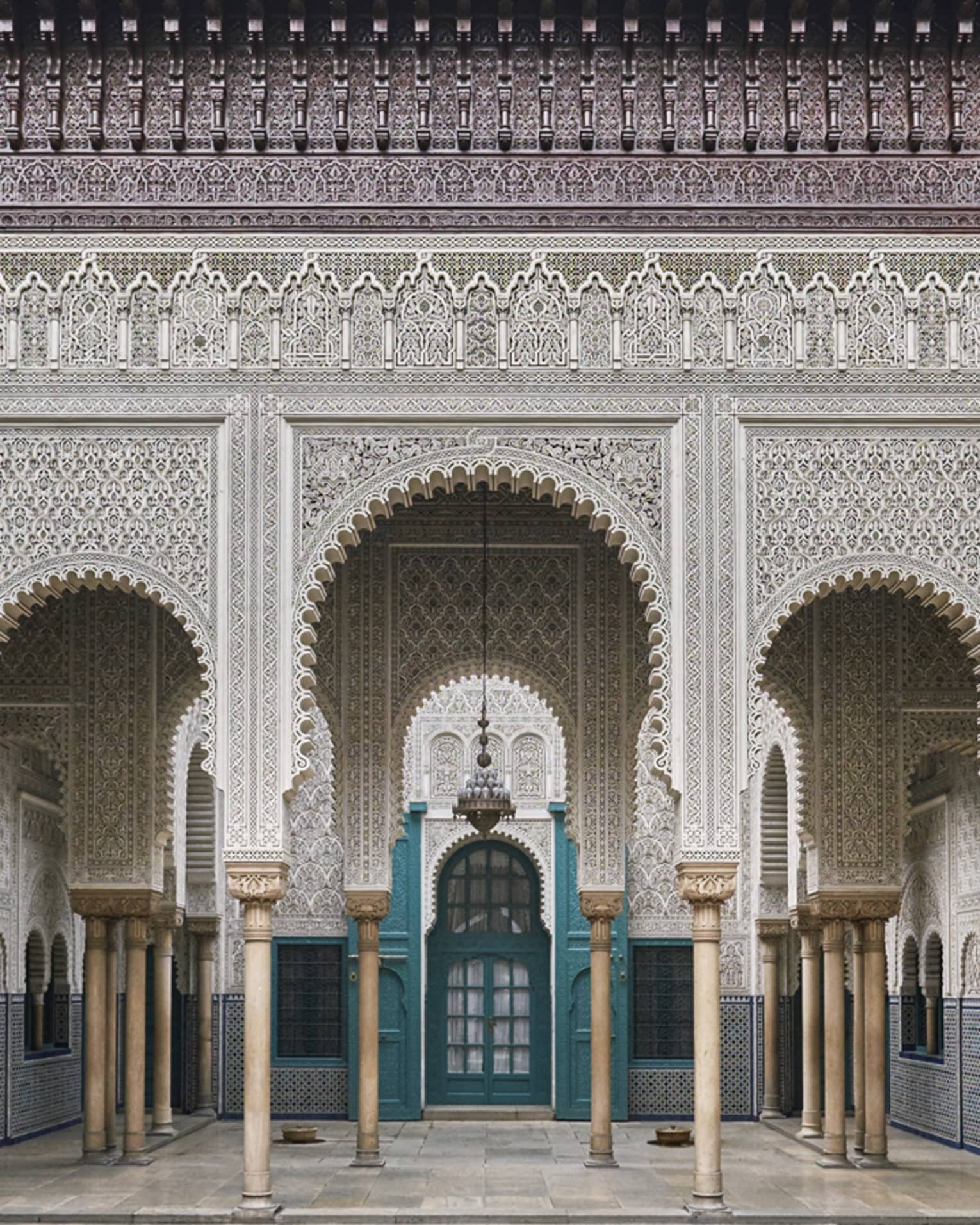 An ancient building with turquoise carved wooden doorways and Moorish influences