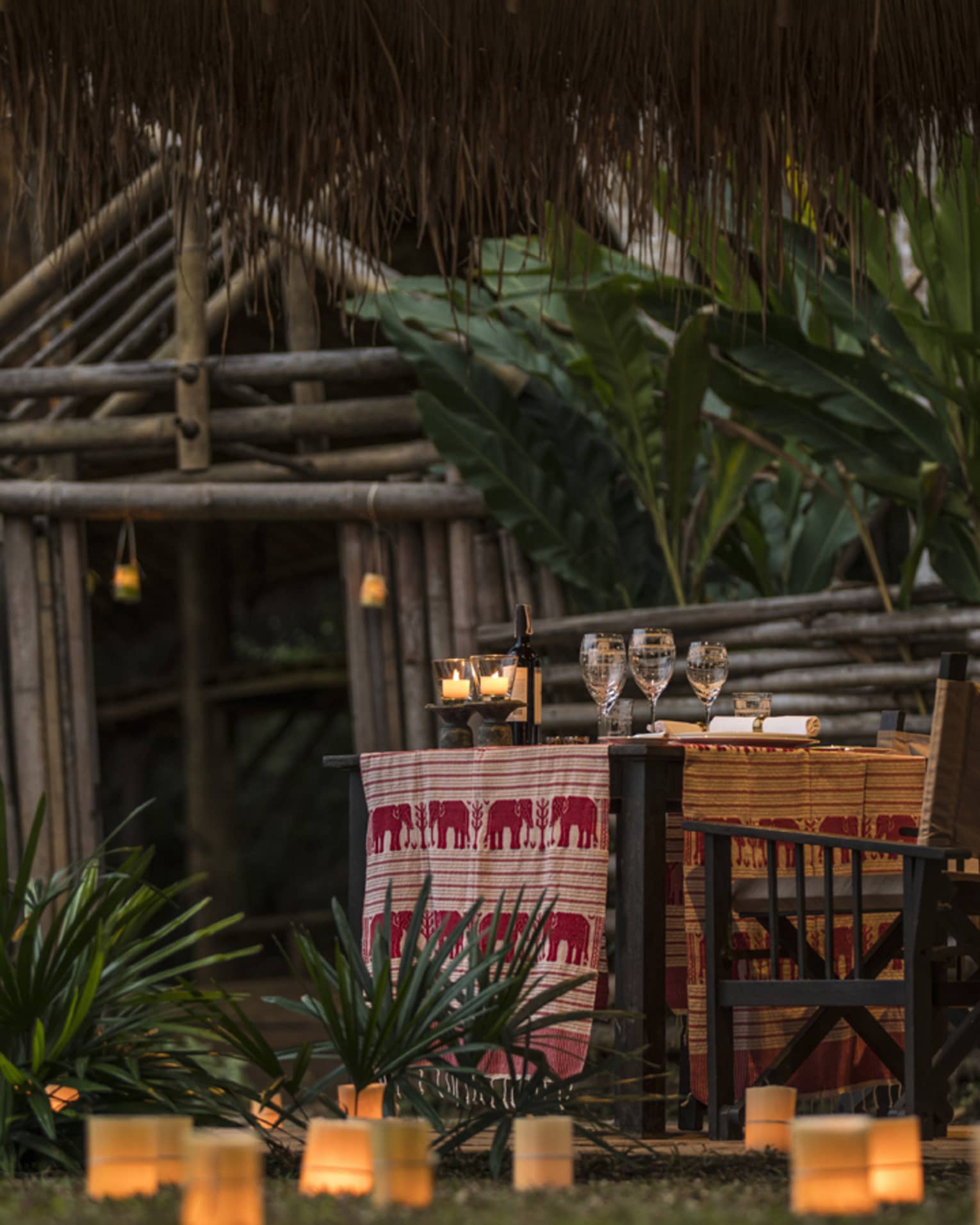 Lanterns along grass leading to dining table with red-and-white elephant textile