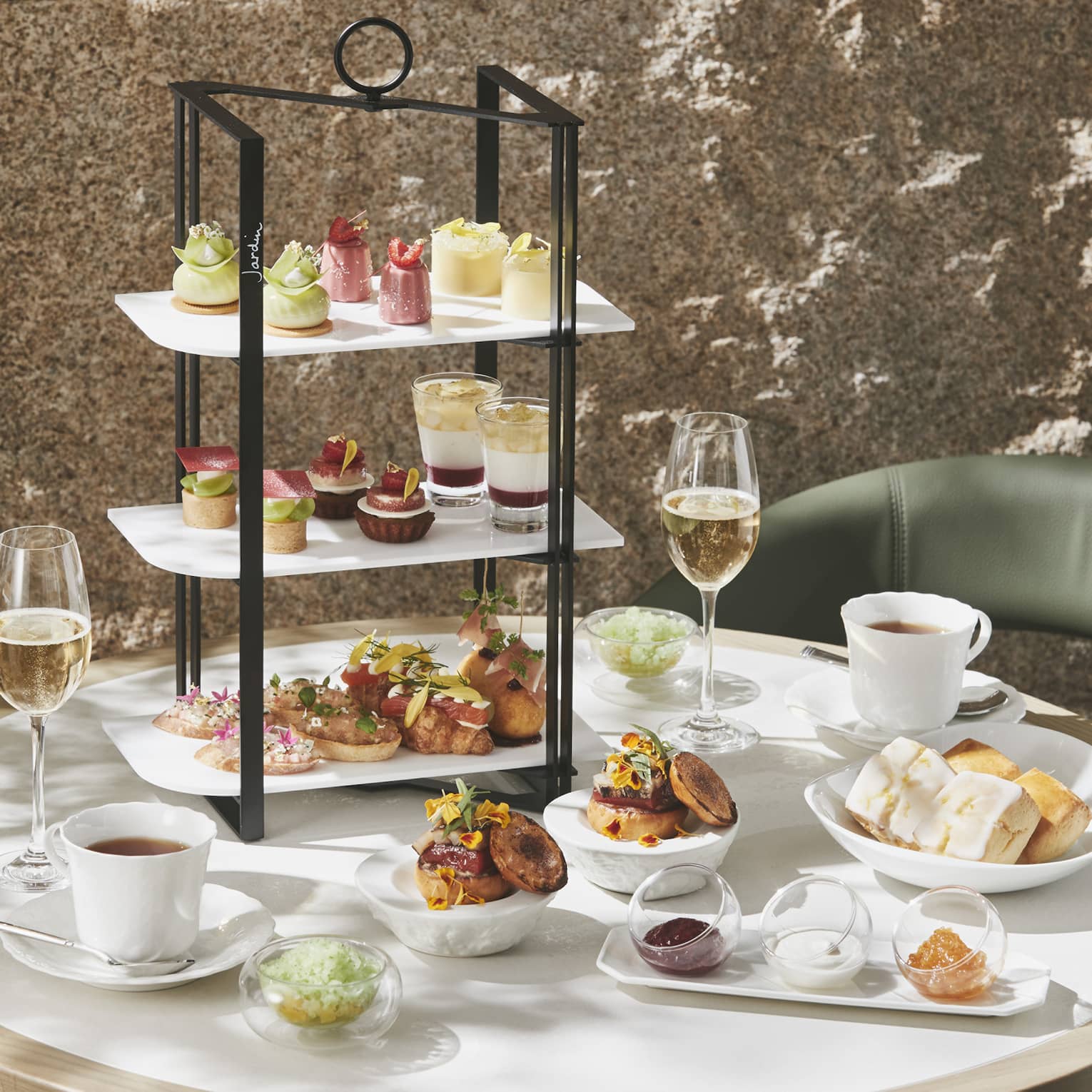 Afternoon Tea set up with three-tiered display of sweet and savoury foods, two glasses of champagne and two glasses of tea