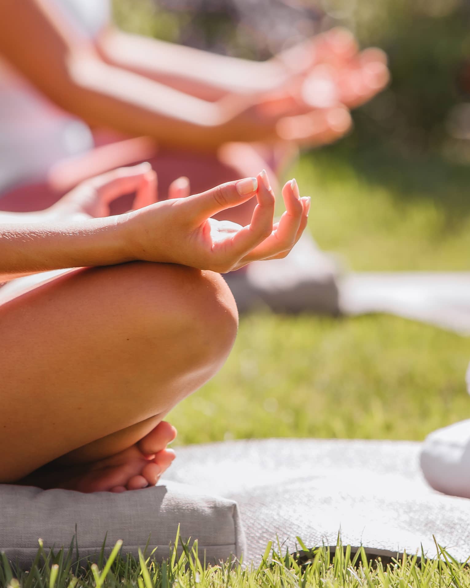 A group doing yoga outside with mats and towels.