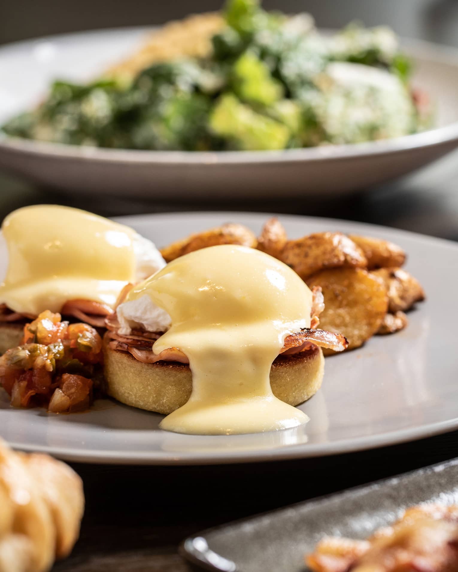 Sunday brunch table with Eggs Benedict, bacon and salad 
