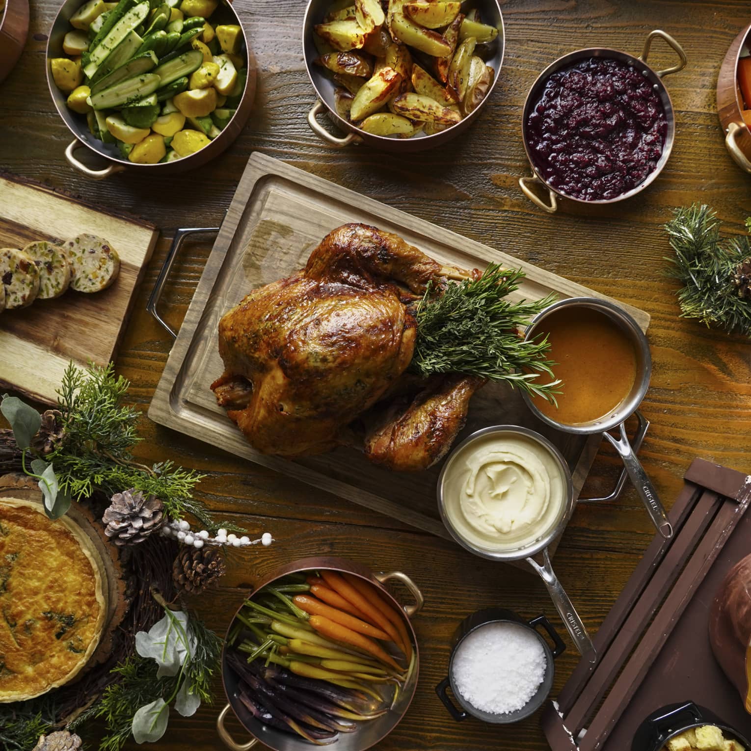 A full festive feast with a Turkey in the centre, and several copper pots of stewed vegetables surrounding