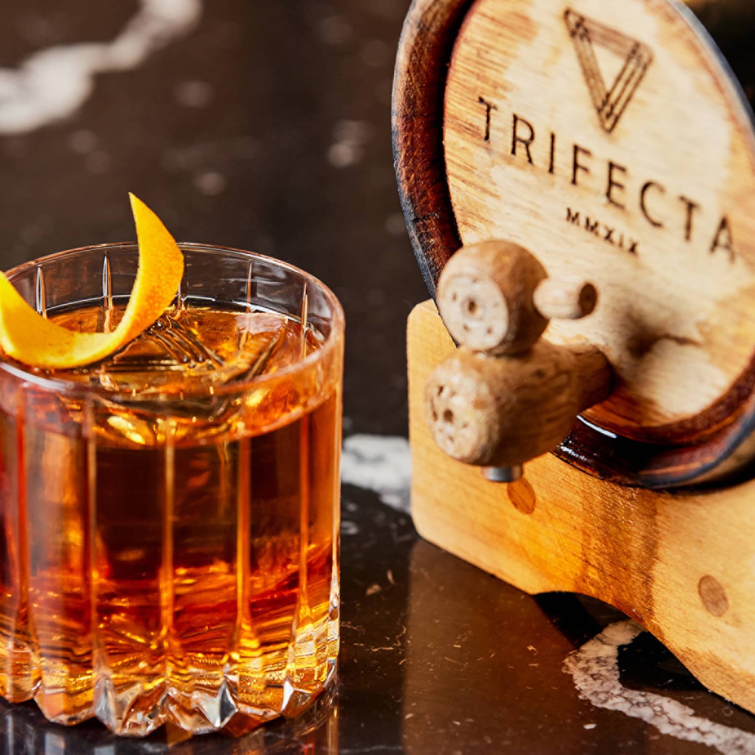An amber coloured cocktail with an orange peel garnish.