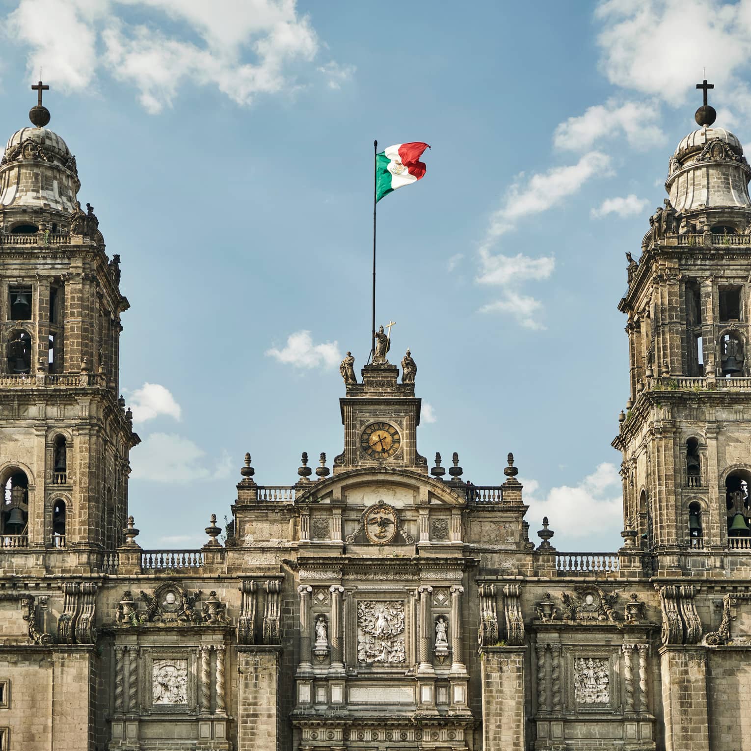 Historic Mexico City building, towers with flag against blue sky