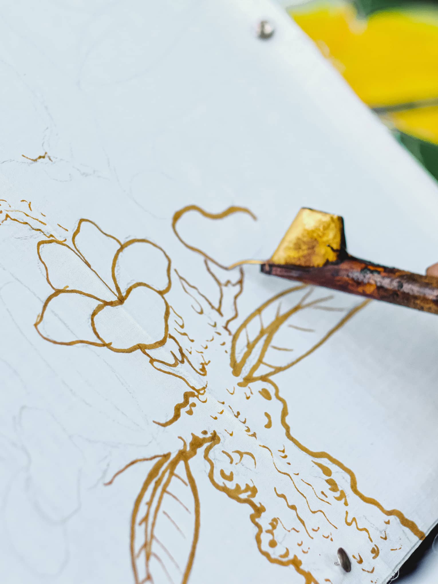 Close-up of man's hand doing batik painting on white canvas