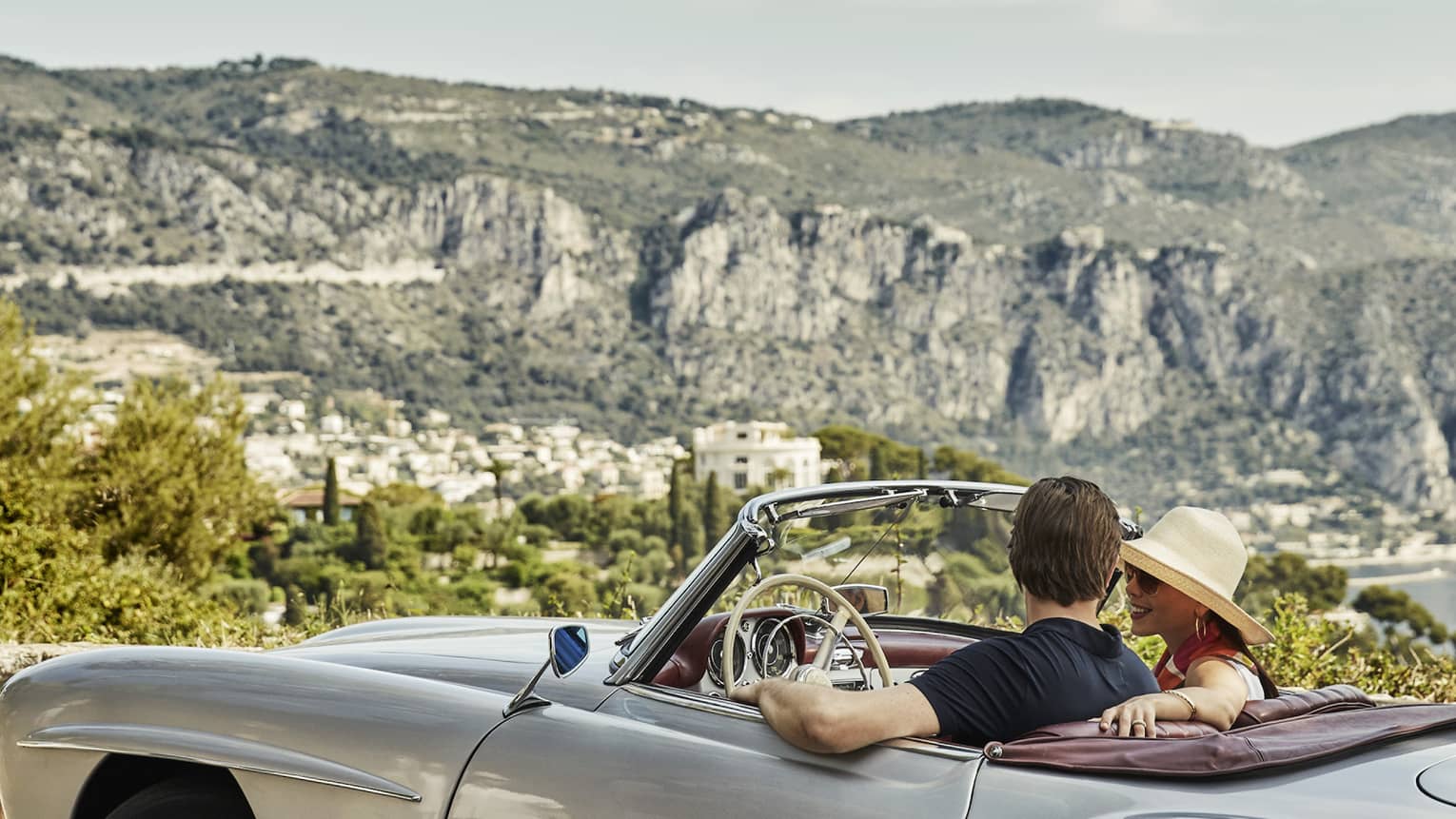 Couple drives in luxury vintage convertible car along French countryside, cliffs