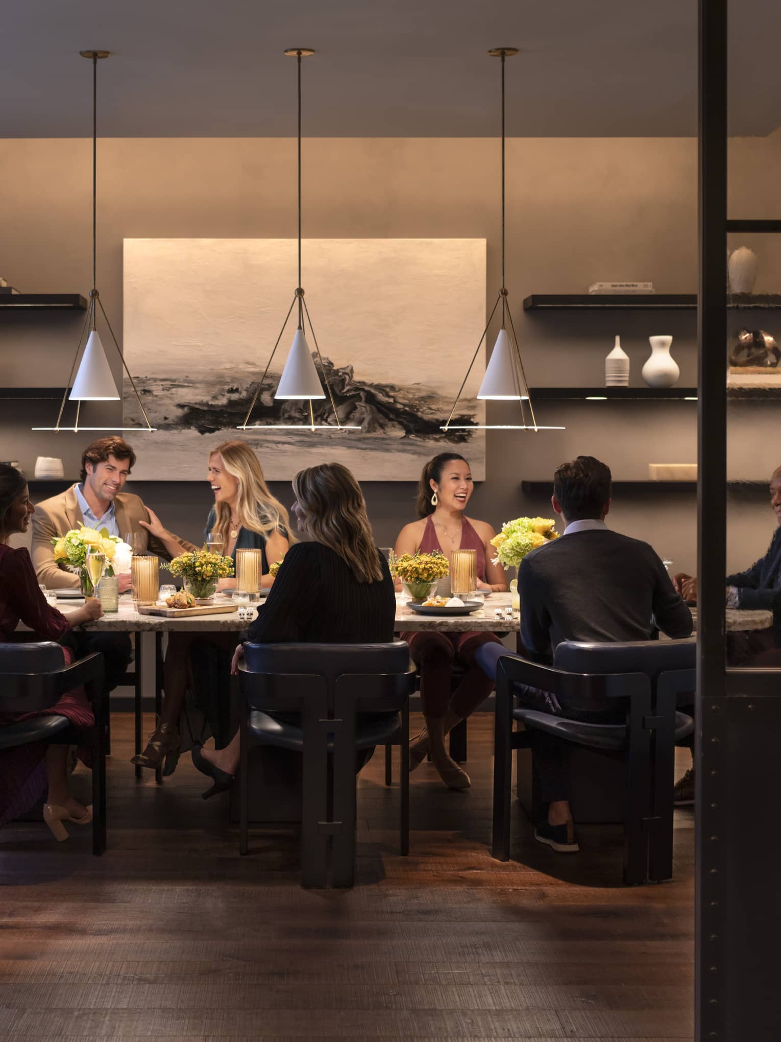 Group of people sitting around dining table and laughing.
