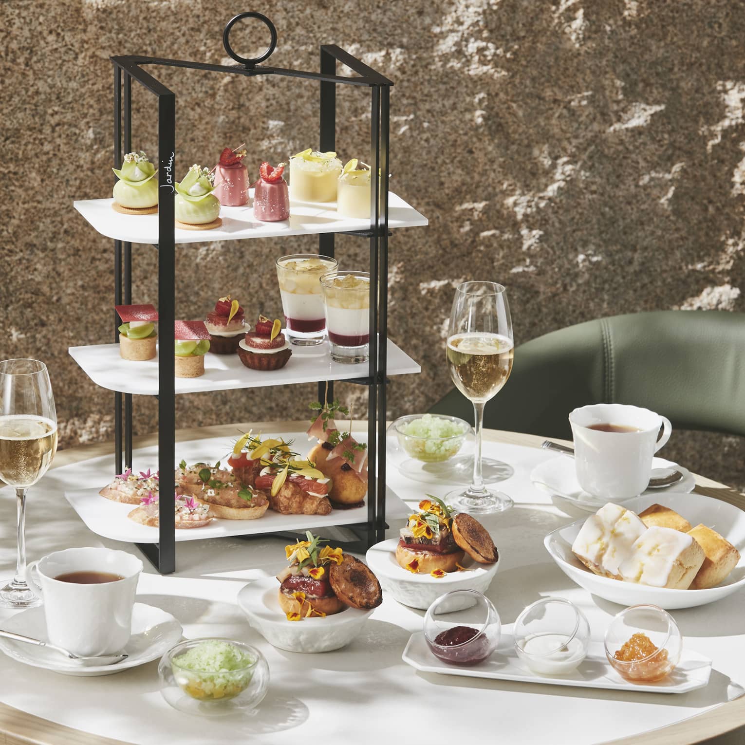 Afternoon Tea set up with three-tiered display of sweet and savoury foods, two glasses of champagne and two glasses of tea