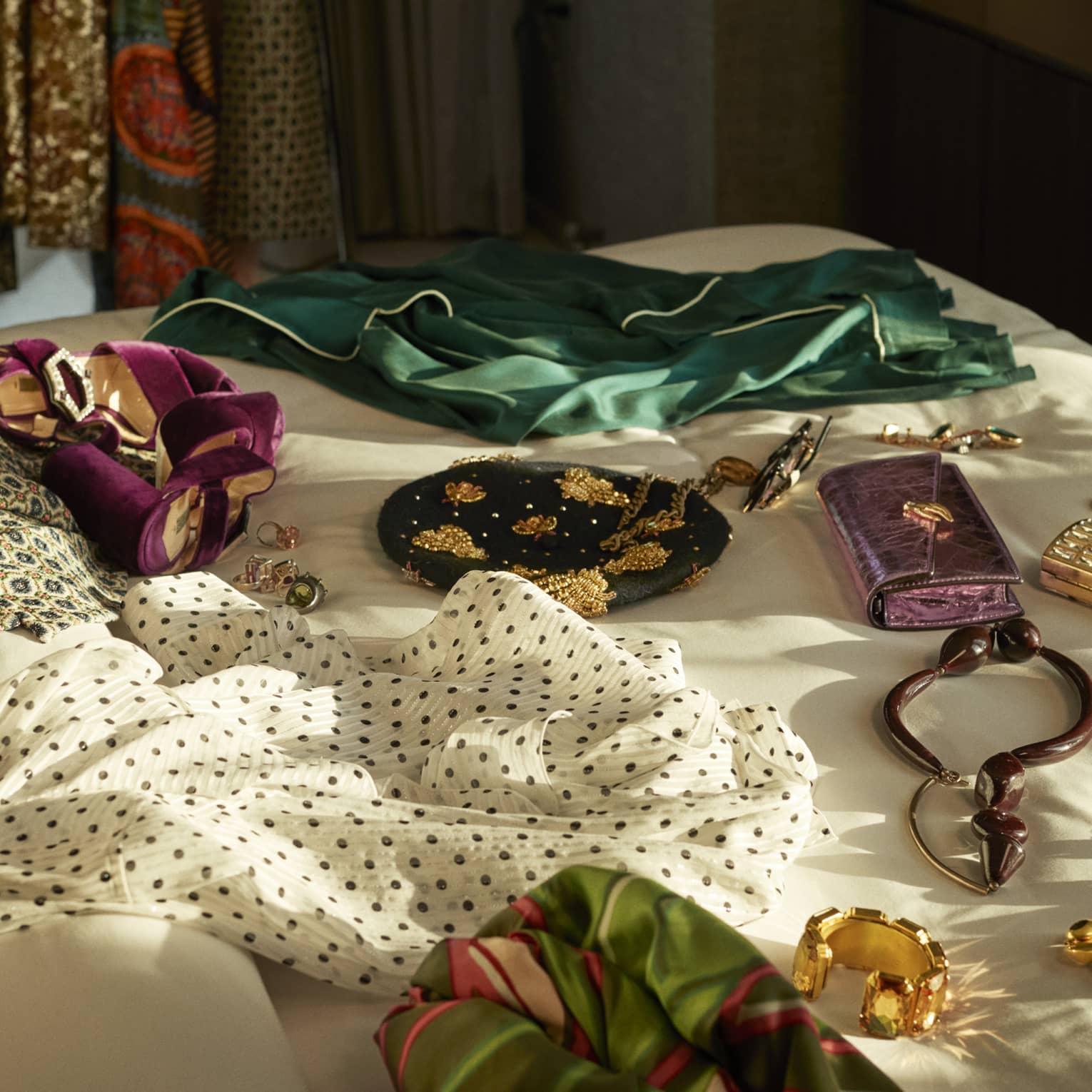 Clothes, gold jewelry and wallets spread out on bed.