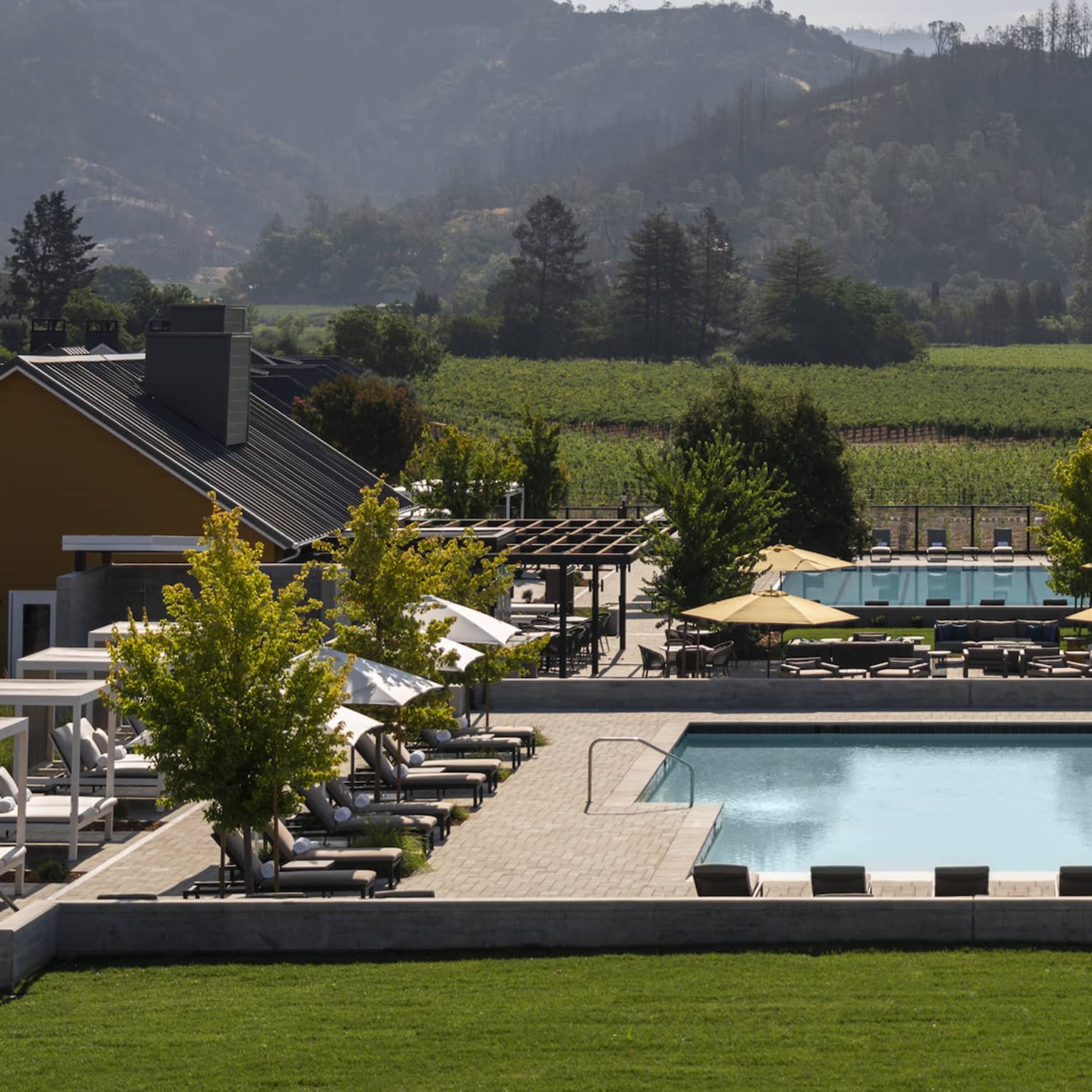Resort pool in Napa Valley, lined with lounge chairs and mountains in distance