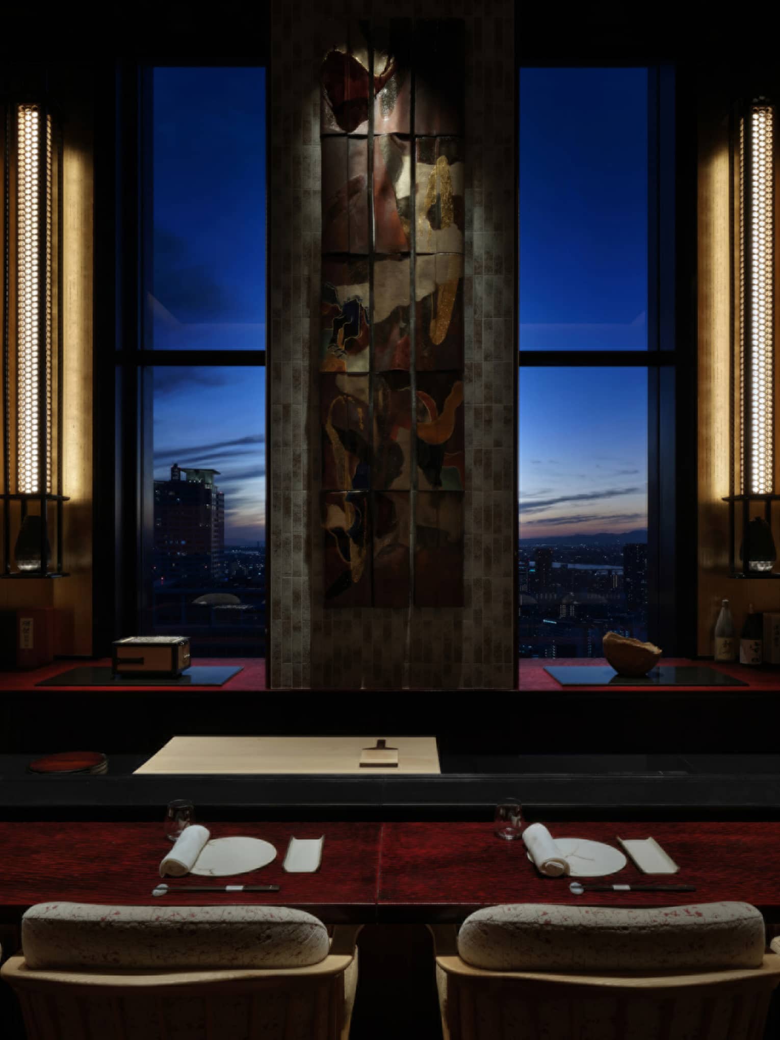 Elegant sushi counter at Sushi L’Abysse Osaka Yannick Alléno, overlooking the city skyline at sunset.