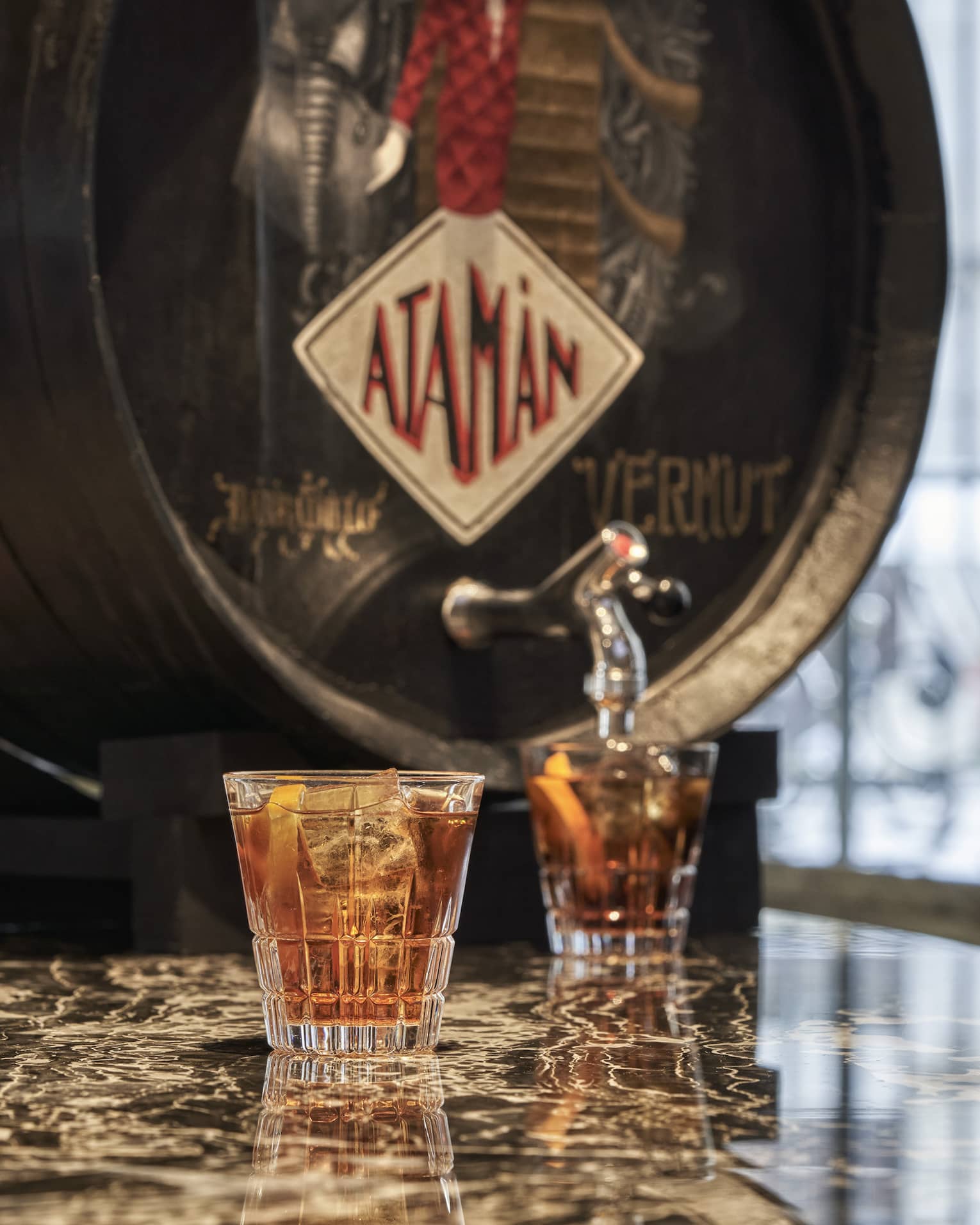 Vermouth cask with two filled cocktail glasses on marble table