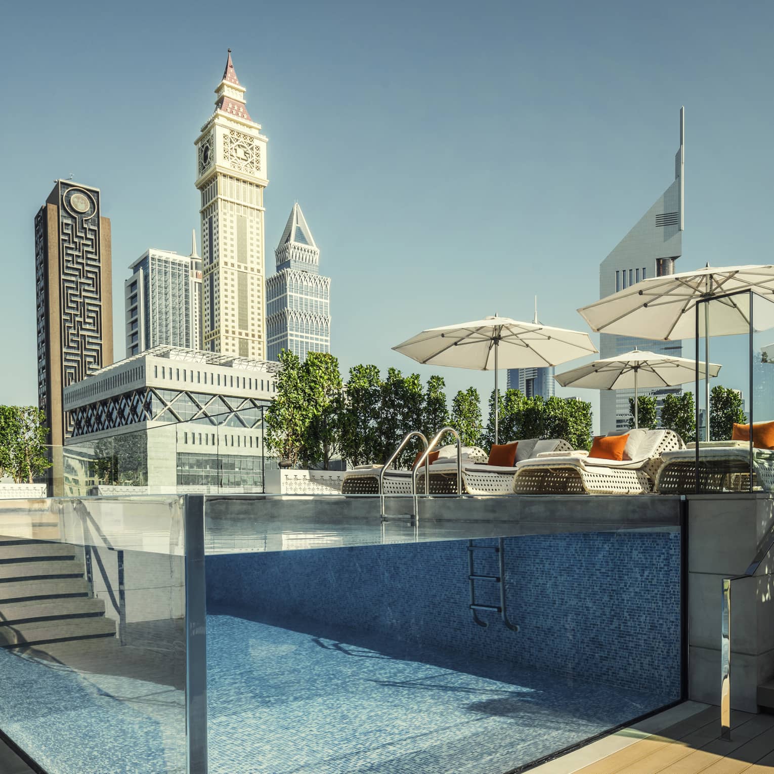 Raised glass plunge pool by stairs on patio deck, lounge chairs, umbrella
