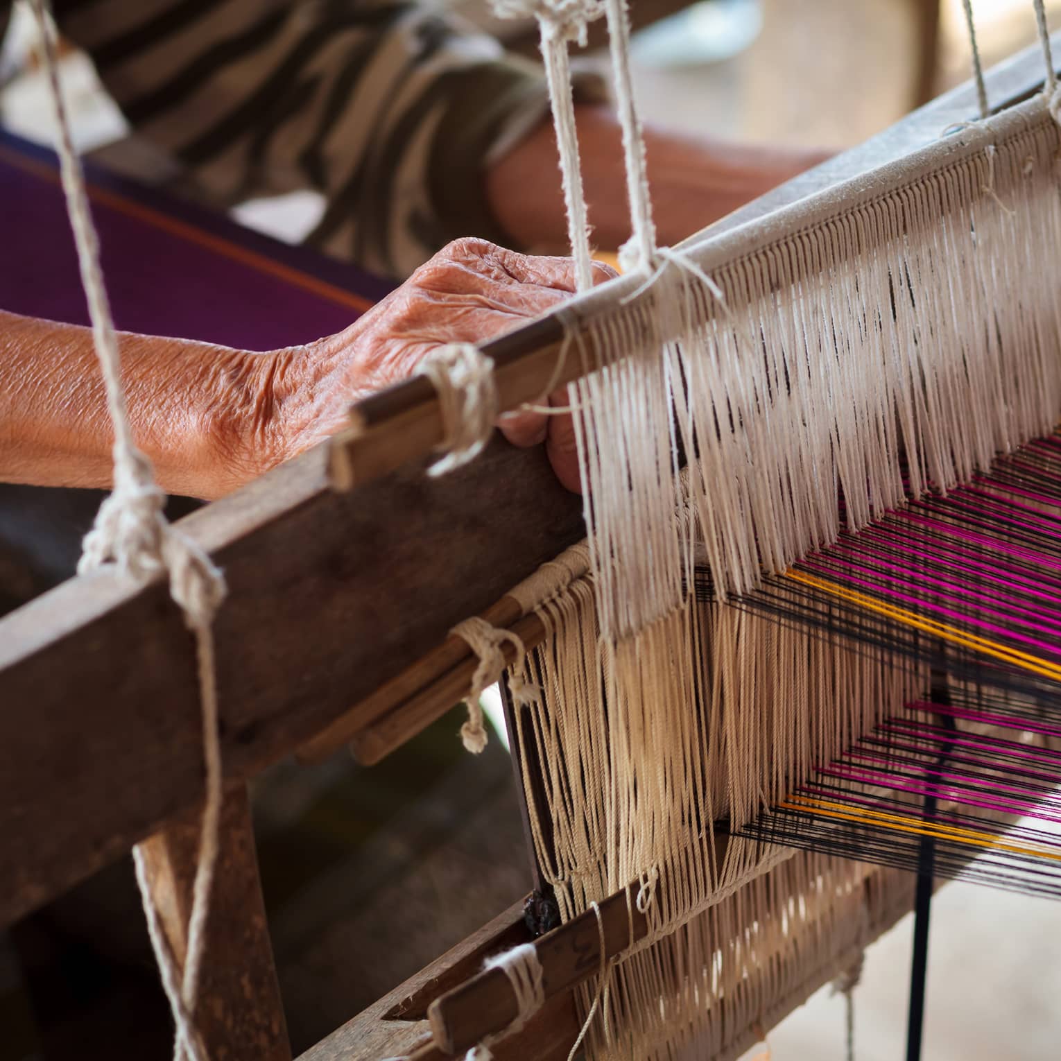 Person using a loom with multi-coloured thread