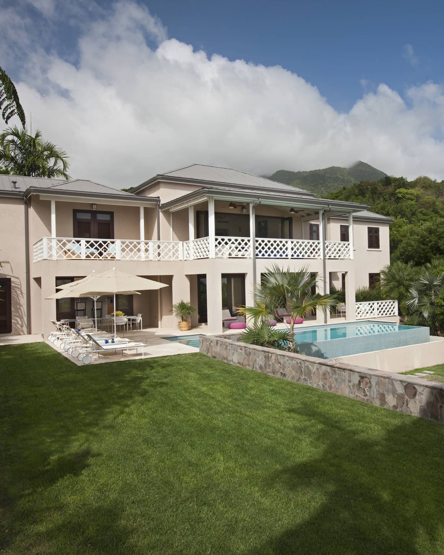 Two storey white villa and plunge pool surrounded by lush greenery