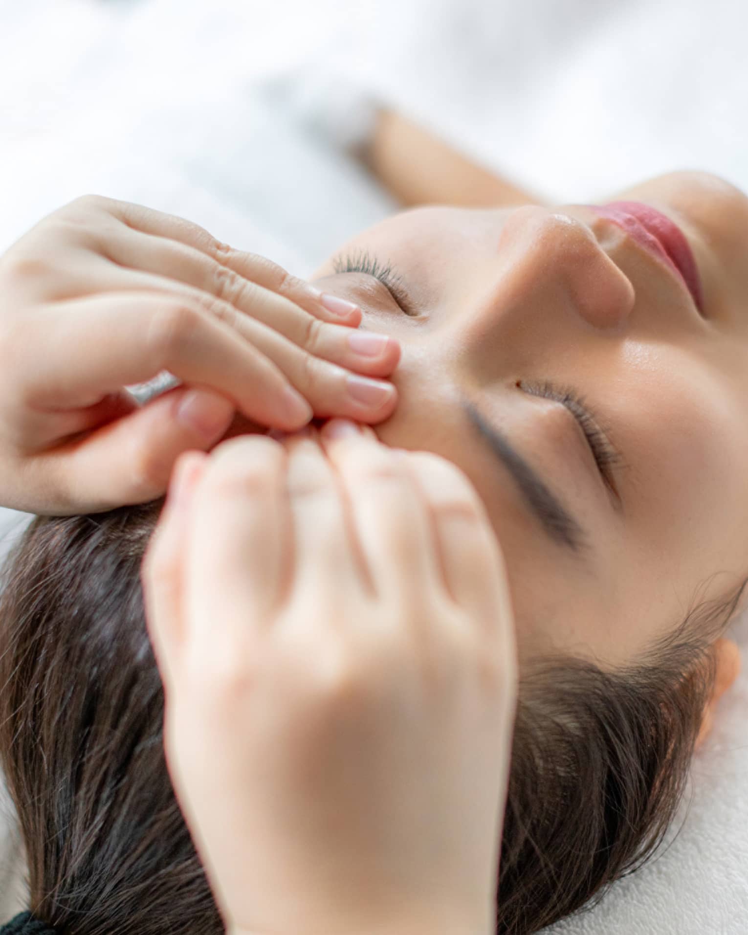 A woman getting a facial massage in a spa.
