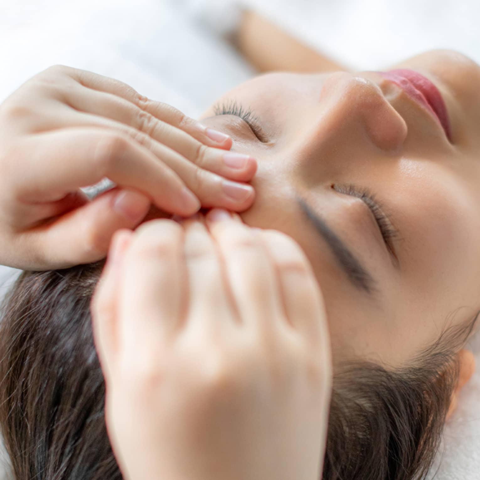 A woman getting a facial massage in a spa.