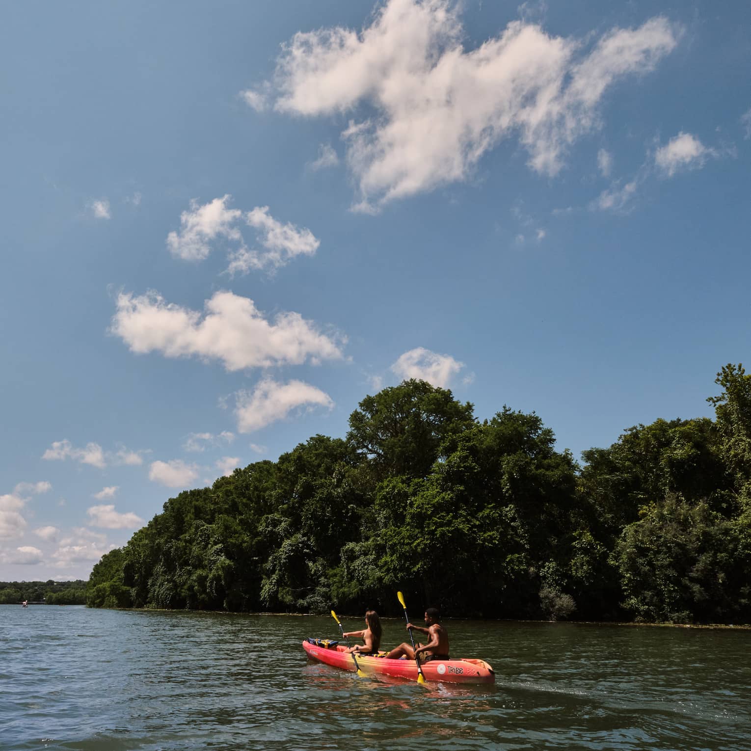Two guests on a kayak using oars to move the kayak through the water