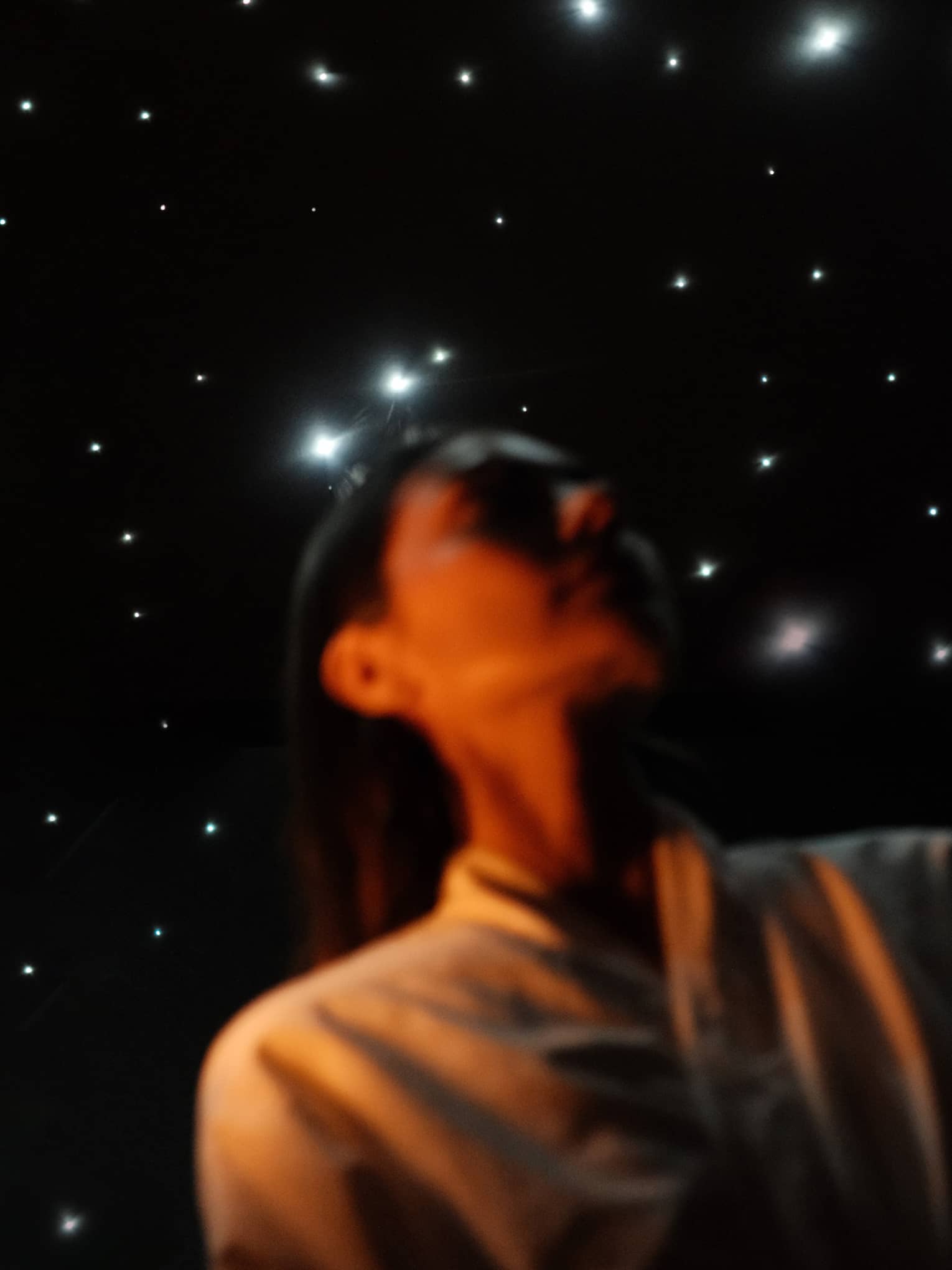 Guest wearing white spa robe stands in front of a ceiling lit to resemble a night sky filled with stars