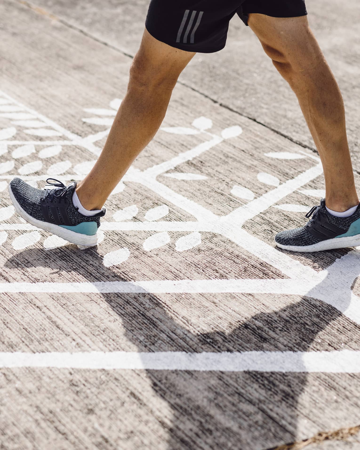 Man in navy blue trainers walks across Four Seasons logo on runway