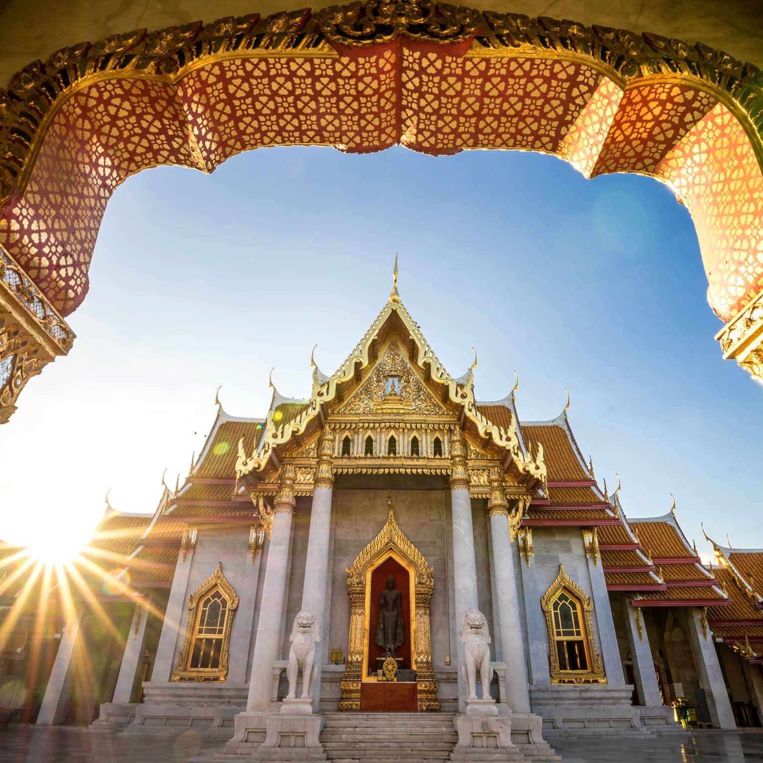 The sun illuminates an ornate temple with golden accents