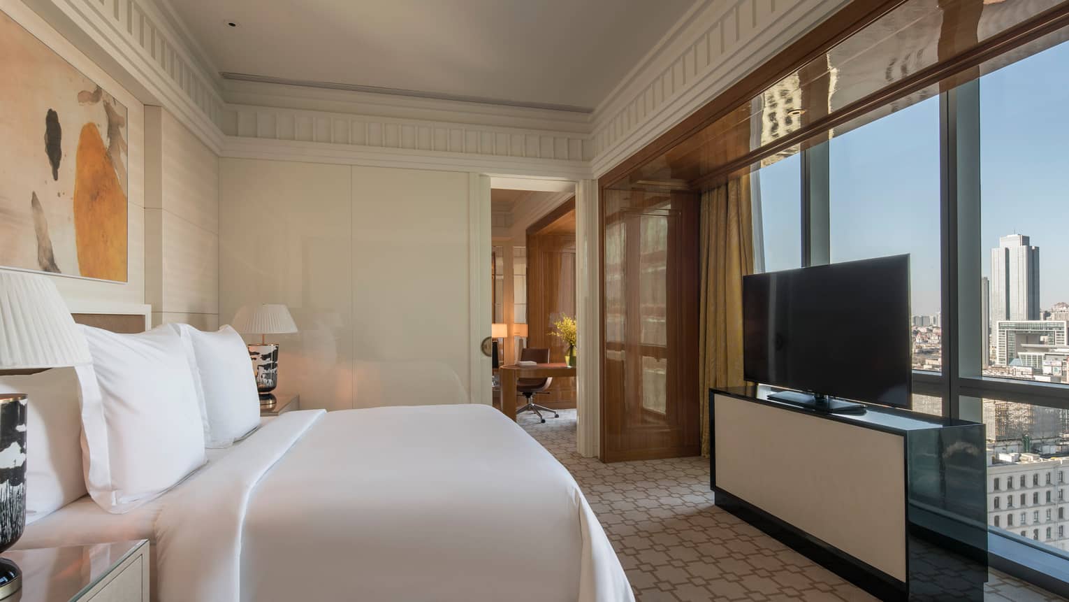 Deluxe Suite bed in front of dresser, TV, large window