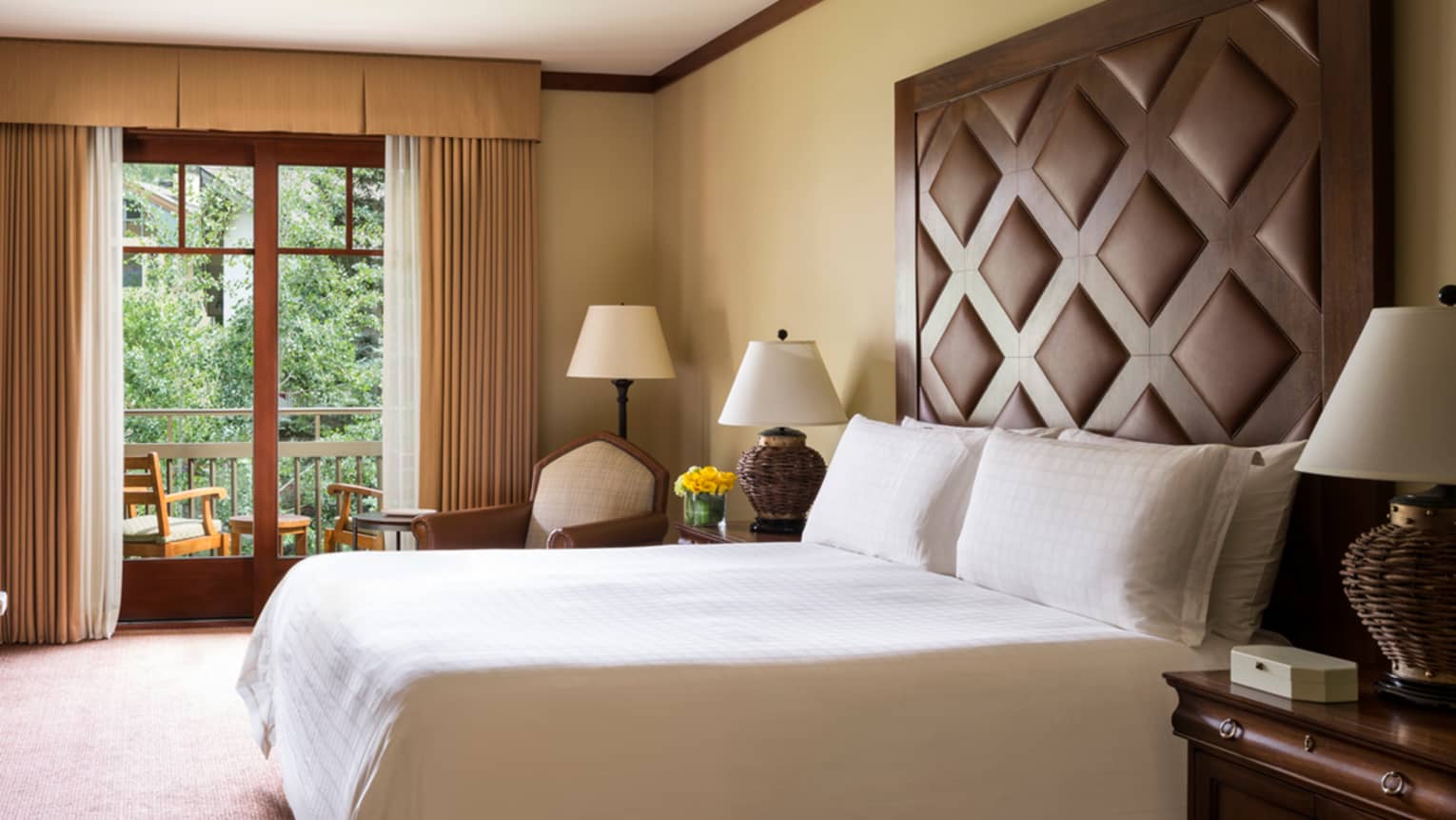 Village View Room bed, gas-burning stone fireplace, balcony with two patio chairs 