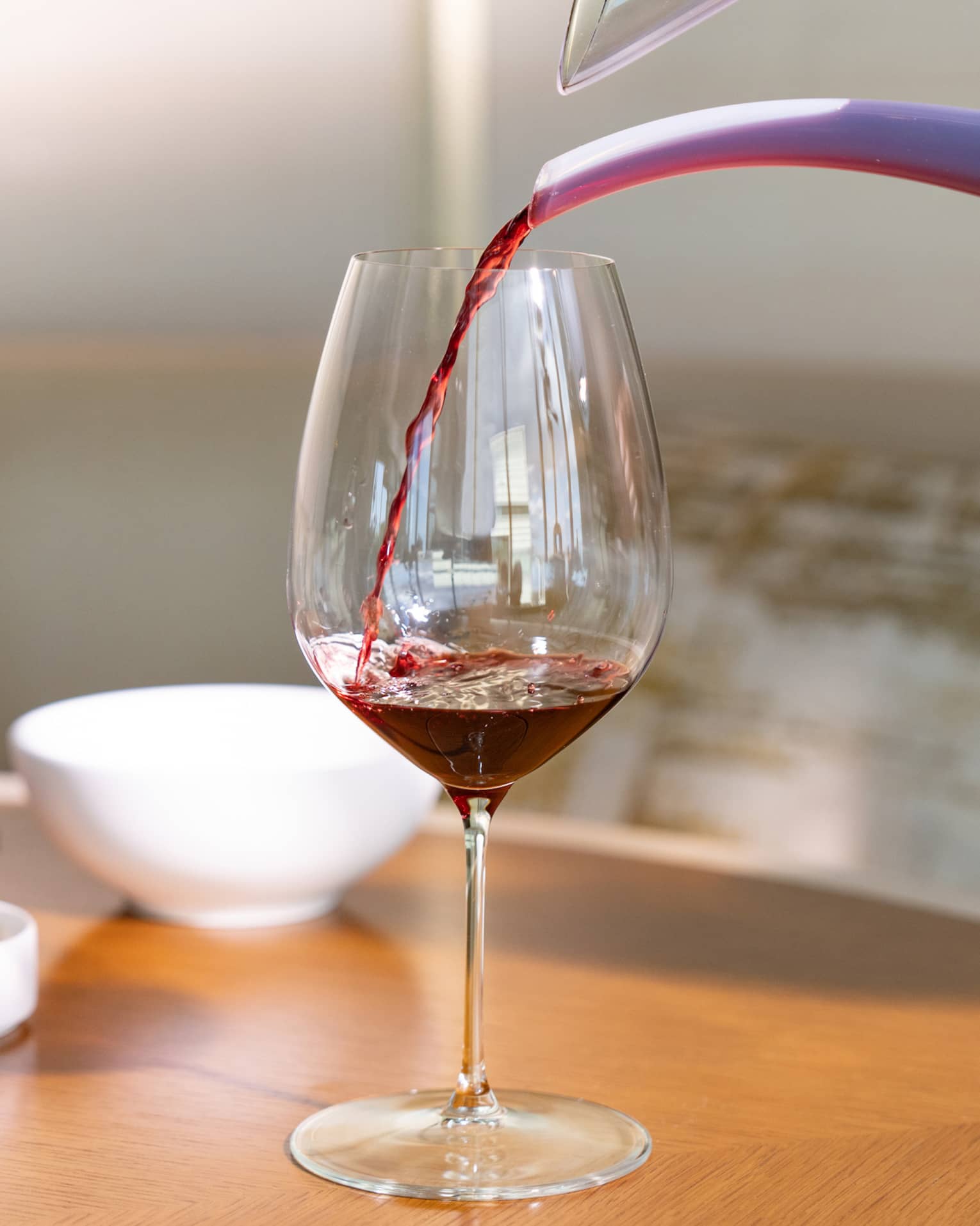 Red wine is poured into a glass from a decanter