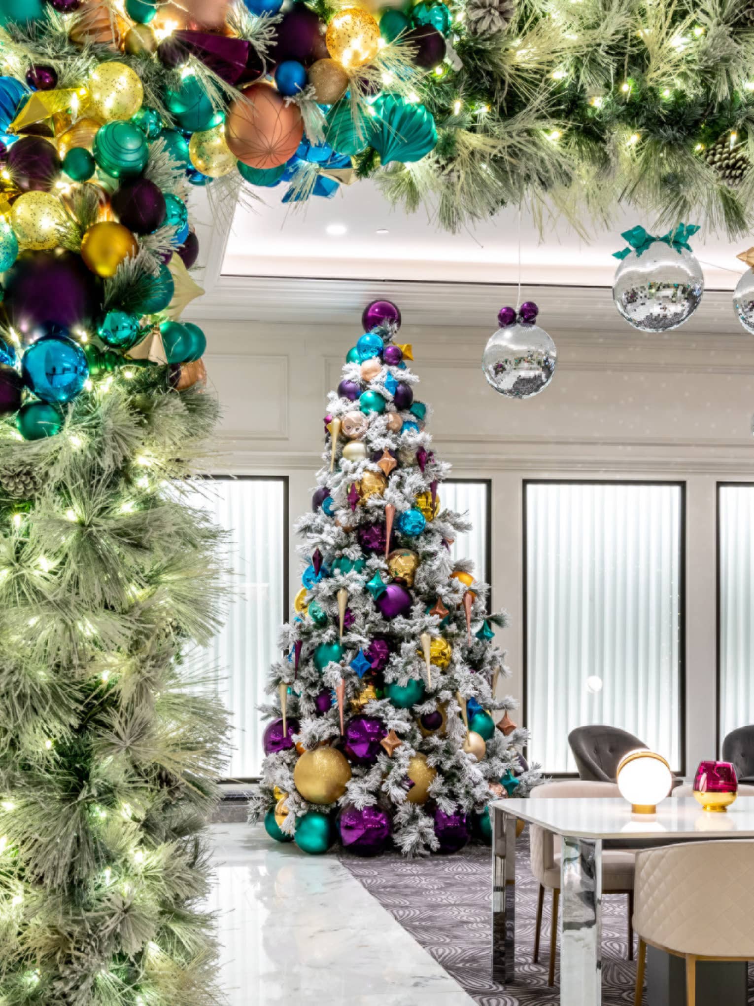 A Christmas tree in a room with table and chairs.
