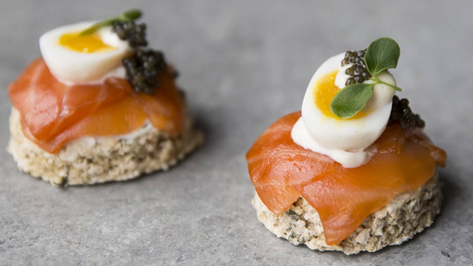 Toast rounds with smoked salmon, soft-cooked quail egg, caviar, microgreens garnish 