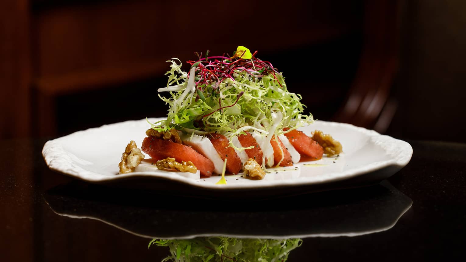 Slices of watermelon and feta topped with lettuce on a white plate