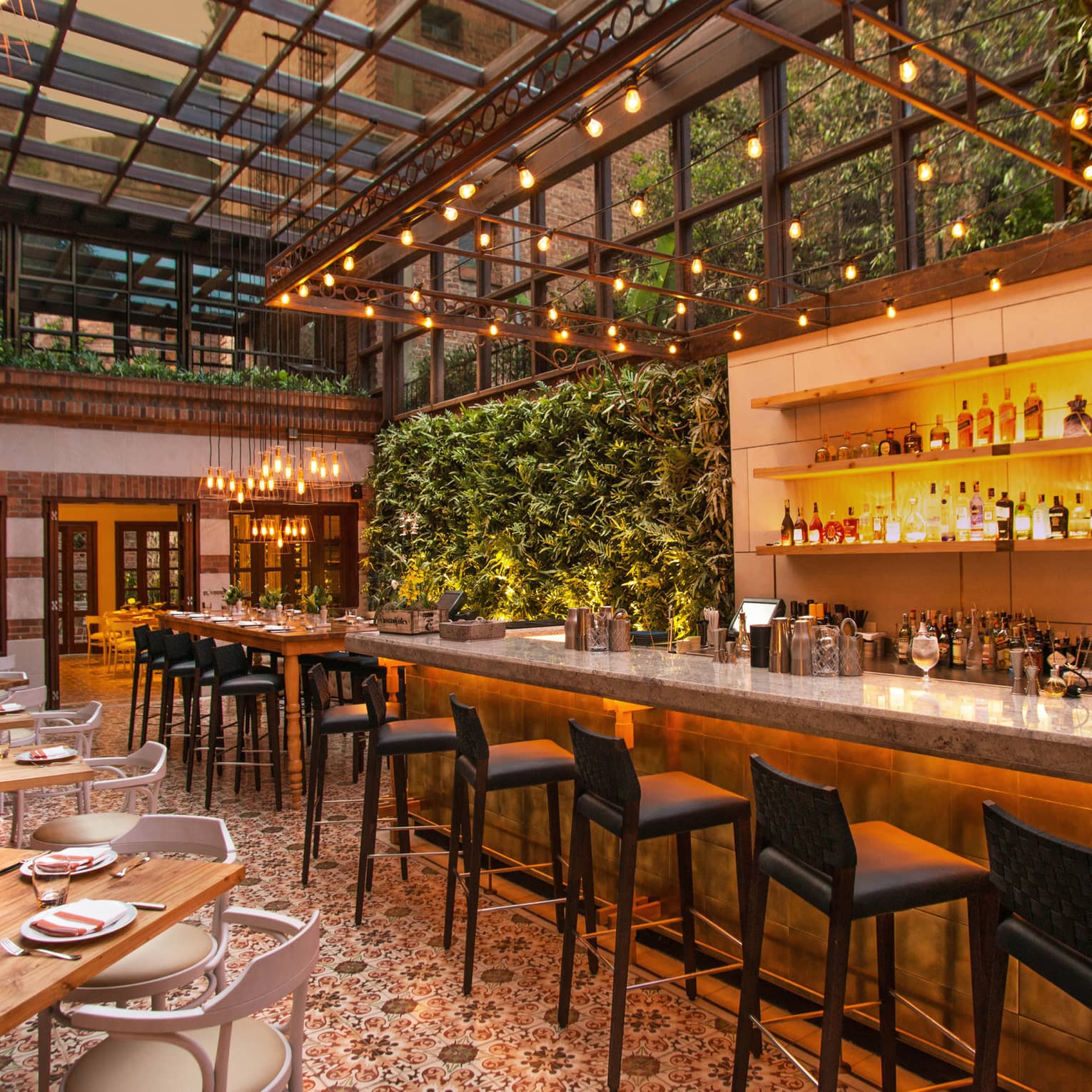 Castanyoles dining room and bar with high ceilings, Spanish-style decor, living walls with lush green plants, patio lights
