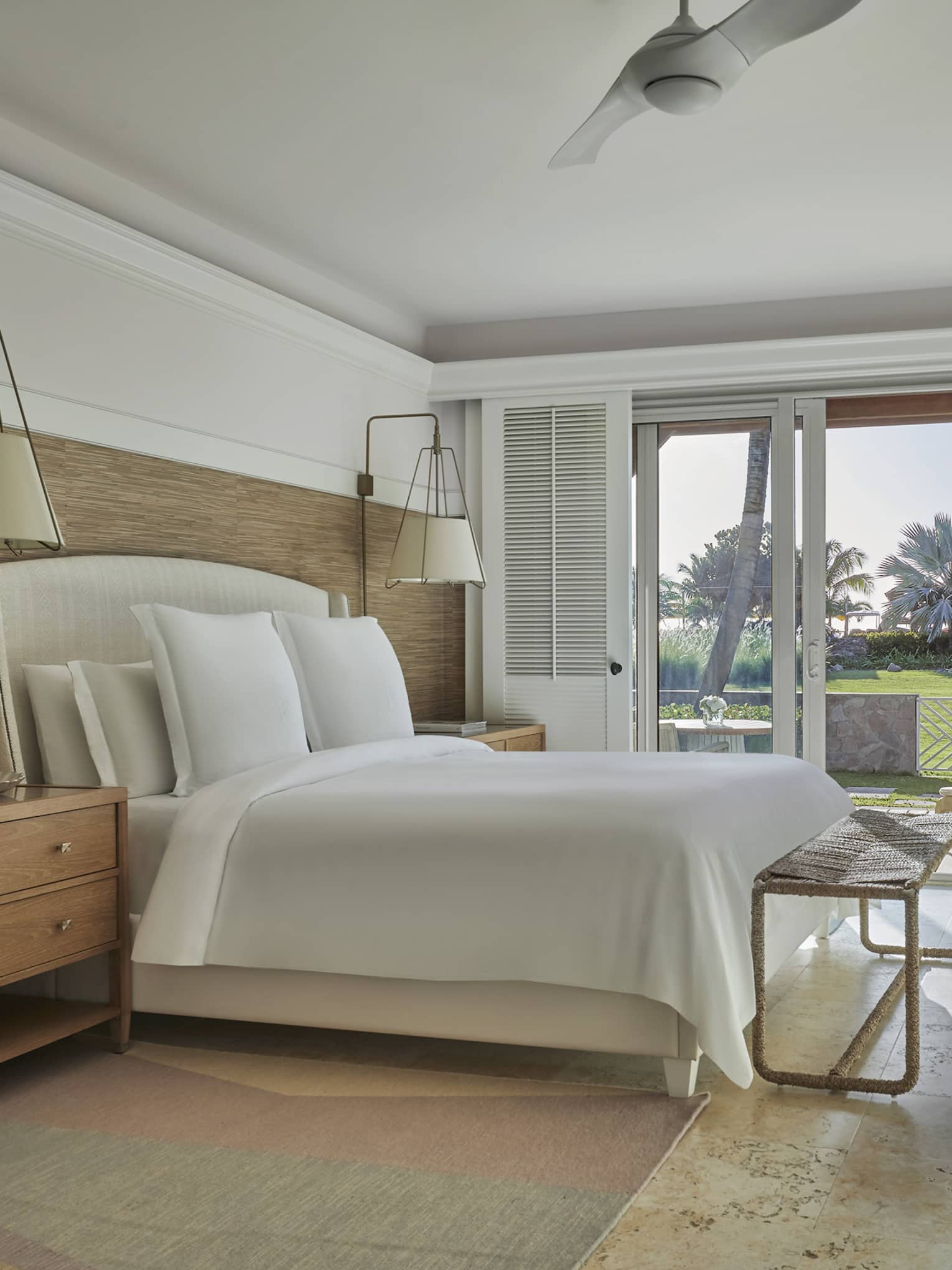 Room with king bed, tan floors, wood side tables, walk-out patio