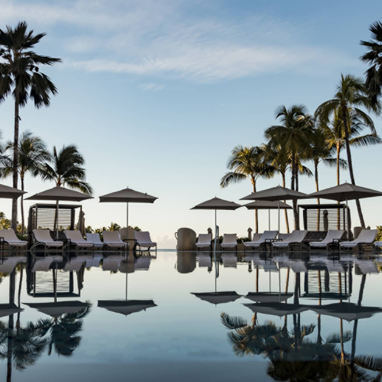 Large pool reflecting the palm trees and lounge chairs around it