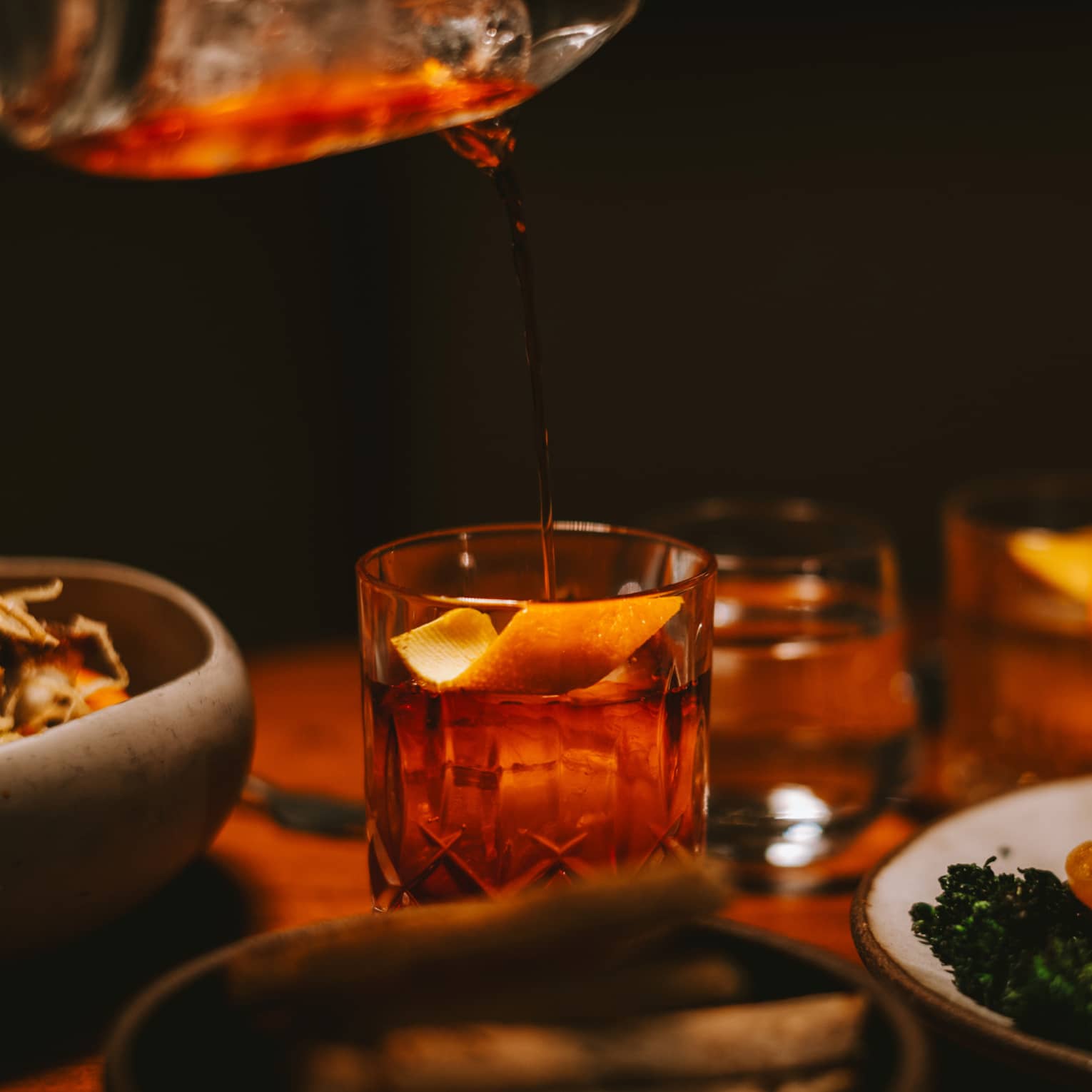 Pouring a drink into a glass with an orange slice.
