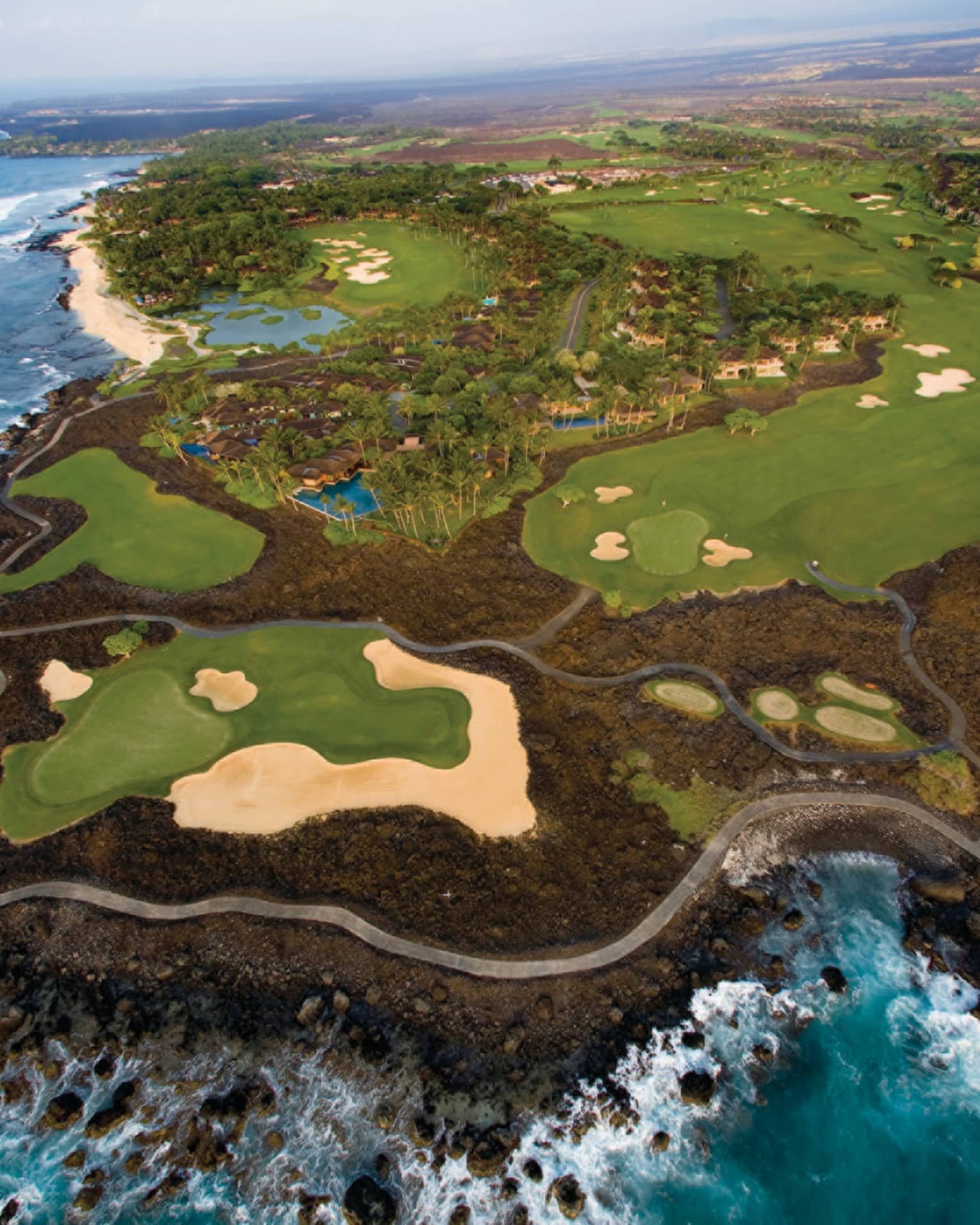 Aerial view of Hualalai Golf Course along rocky shore and ocean